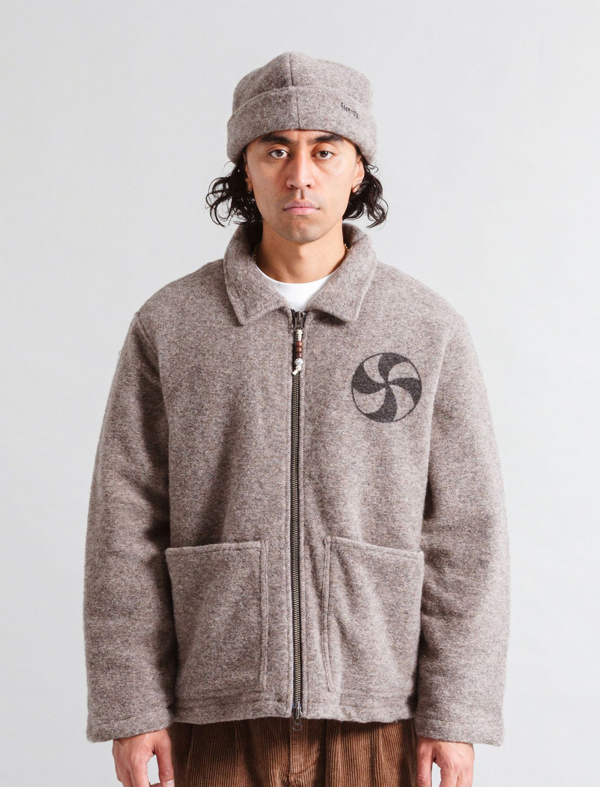 Person wearing a gray fleece jacket with a logo on a plain background