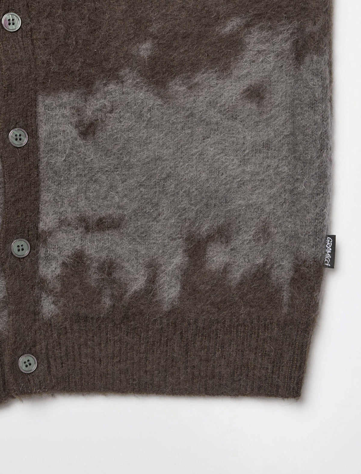 Close-up of a brown and gray marbled knit cardigan sweater with a ribbed button-down front and a small black brand tag reading 'LUXE'.