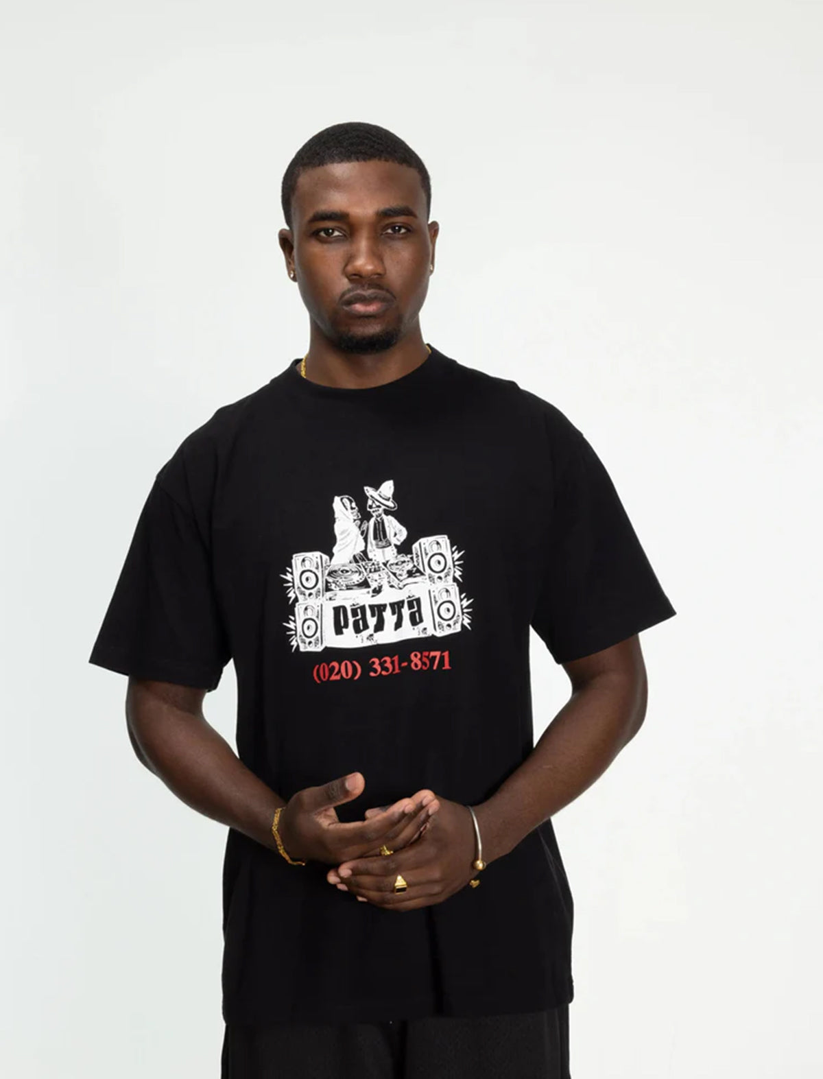 Man wearing a patta black t-shirt with a graphic design on a white background