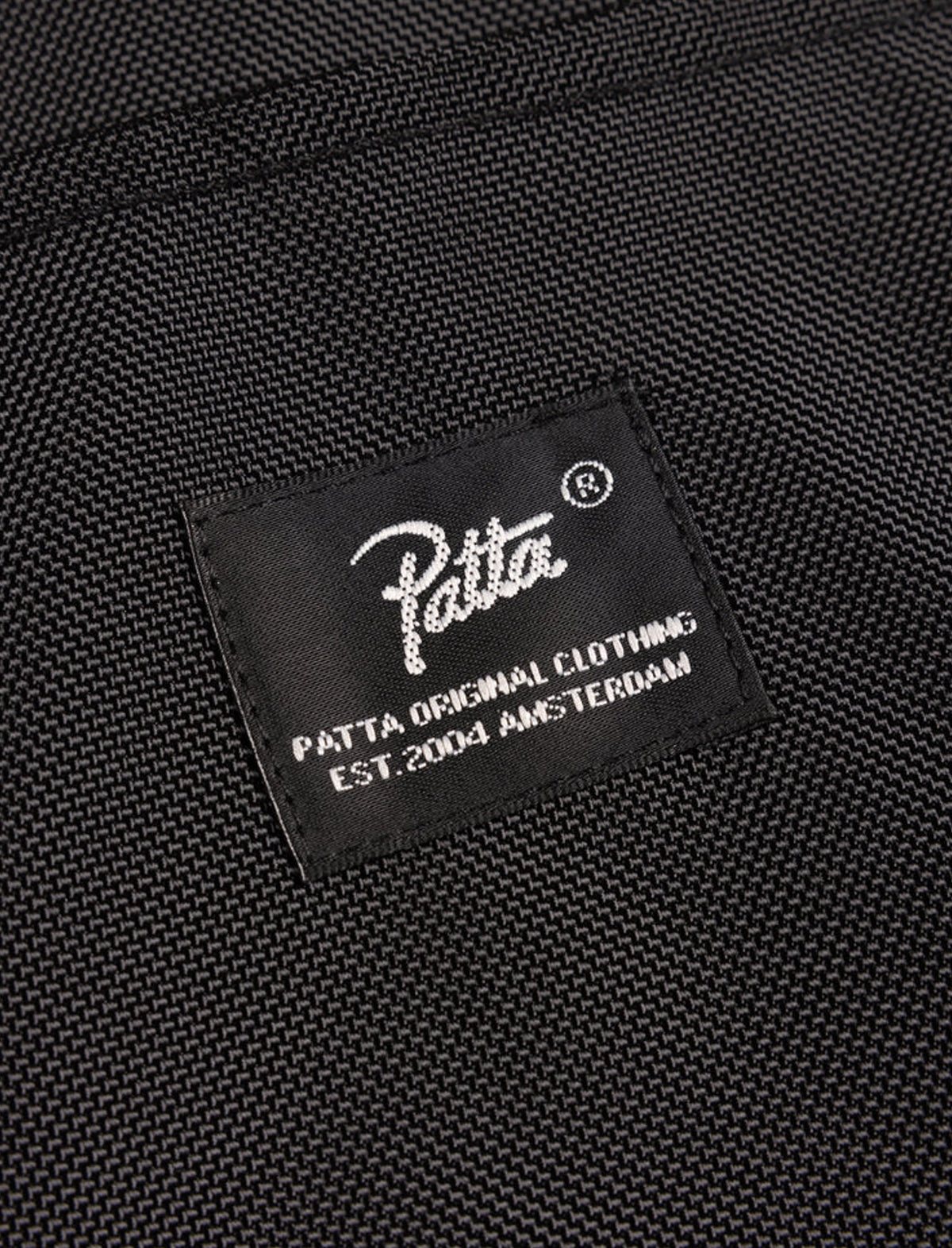 Patta label on a black textured fabric background