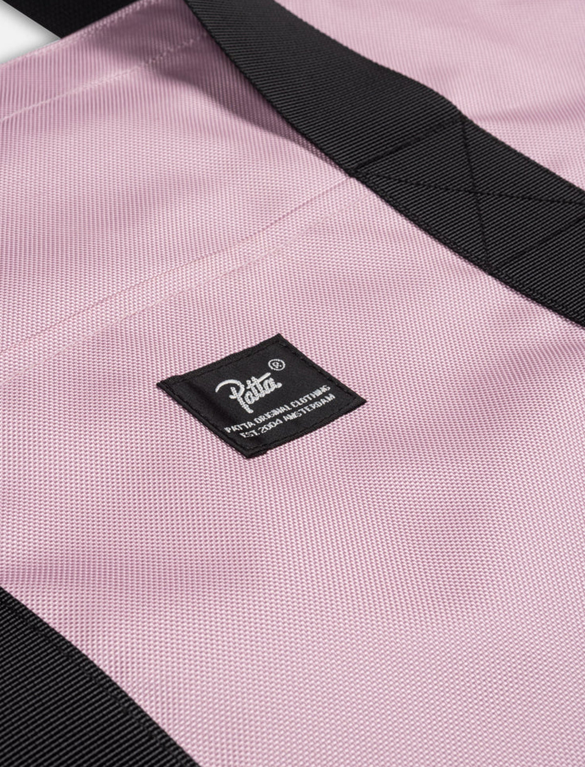 Close-up of a pink Patta bag with a black strap and visible brand label.