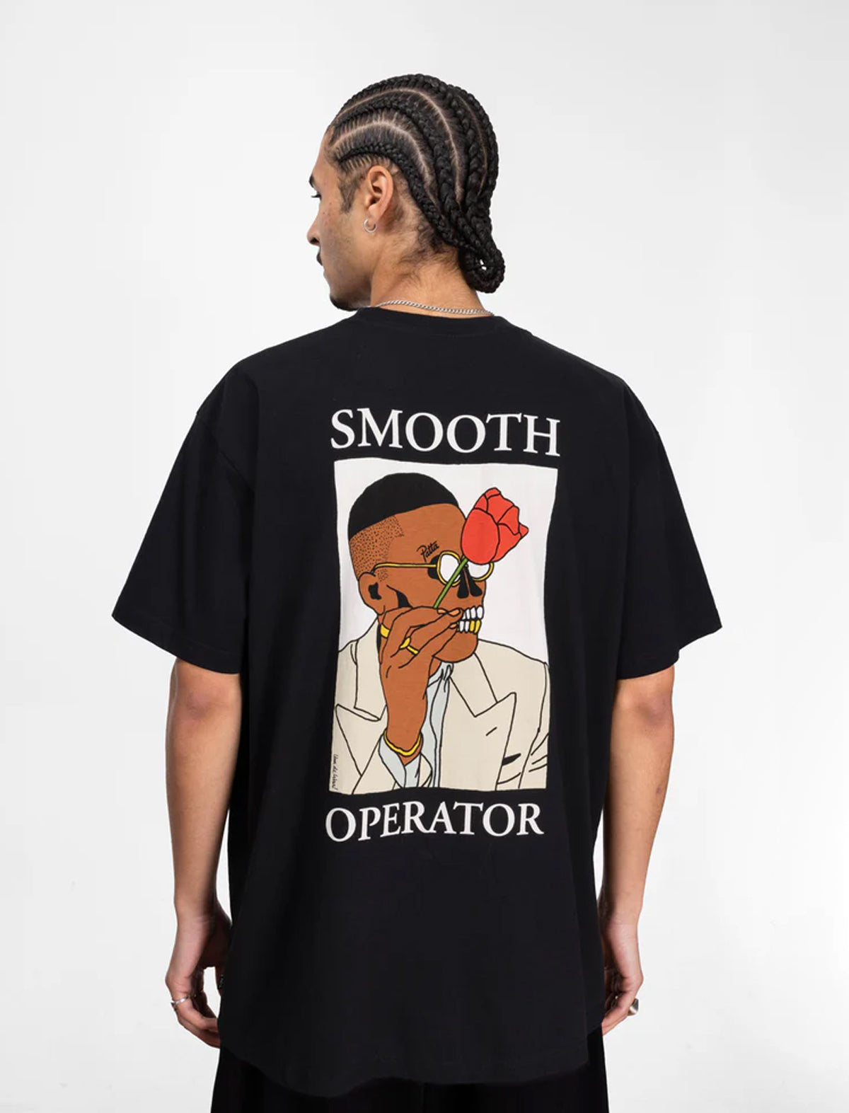 Person wearing a black Patta t-shirt with a graphic design on the back, featuring text and an illustration.