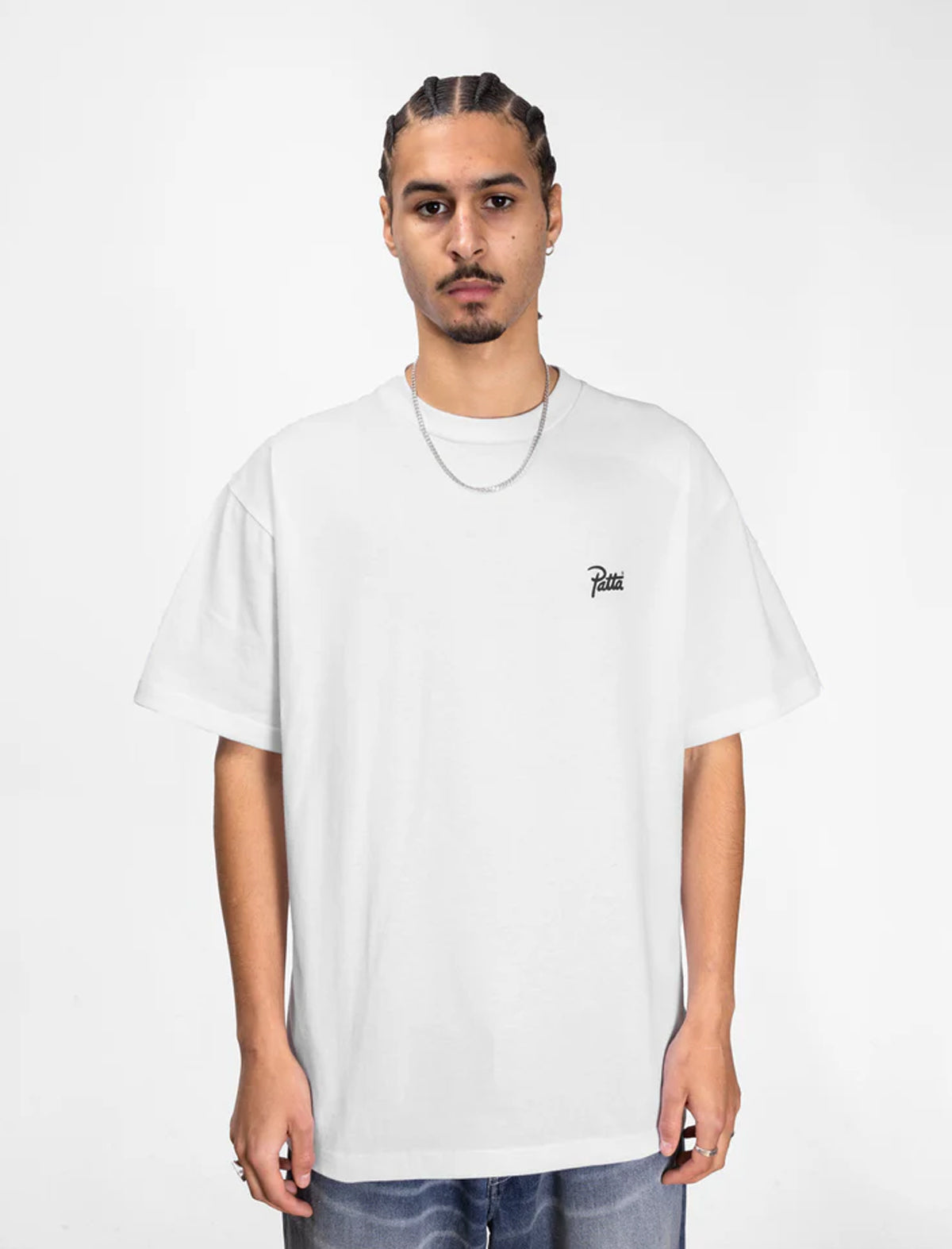 Person wearing a white Patta t-shirt with a small logo on a plain background
