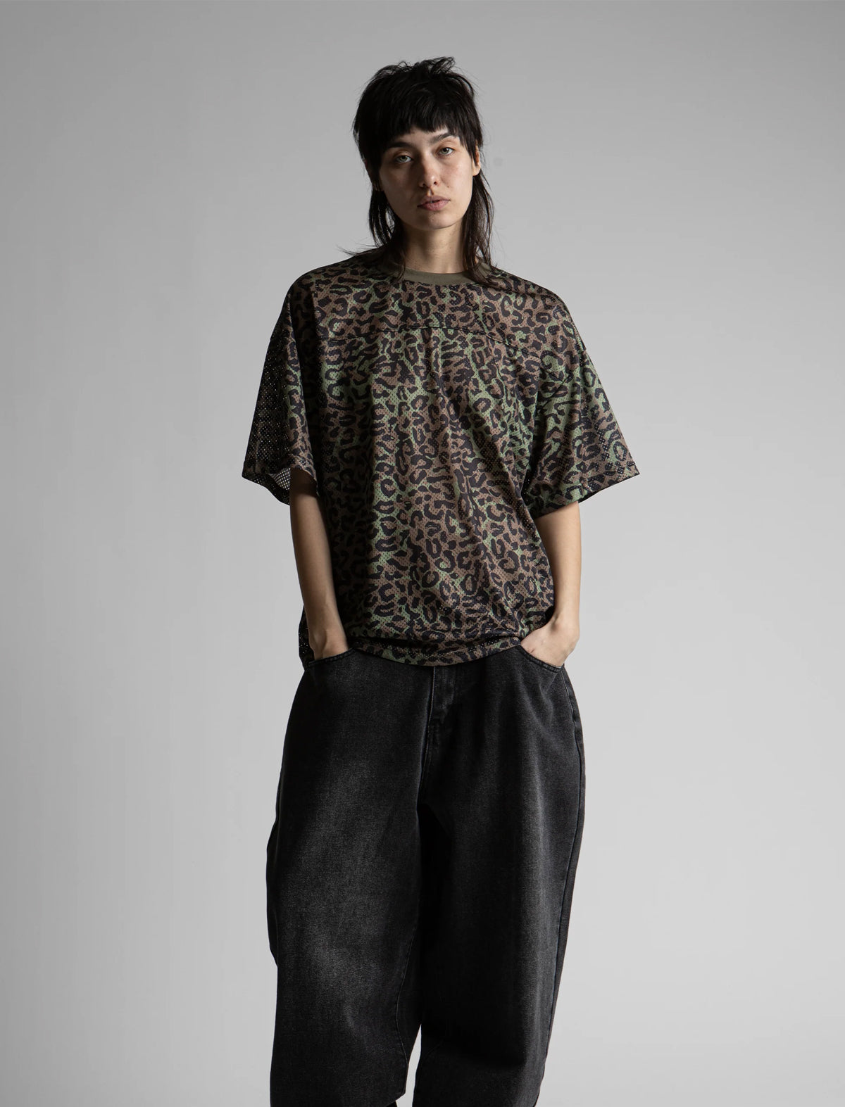 Person wearing a sheer leopard print top and black pants on a plain background