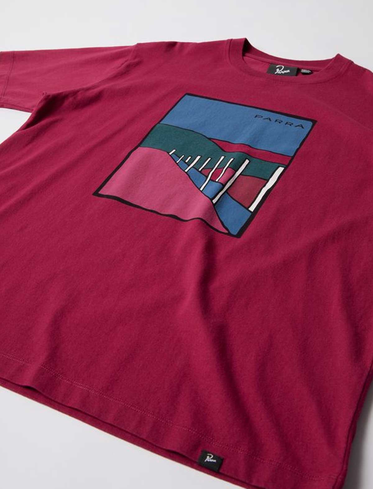 By Parra Beach Parking Maroon t-shirt with a colorful graphic design on a white background