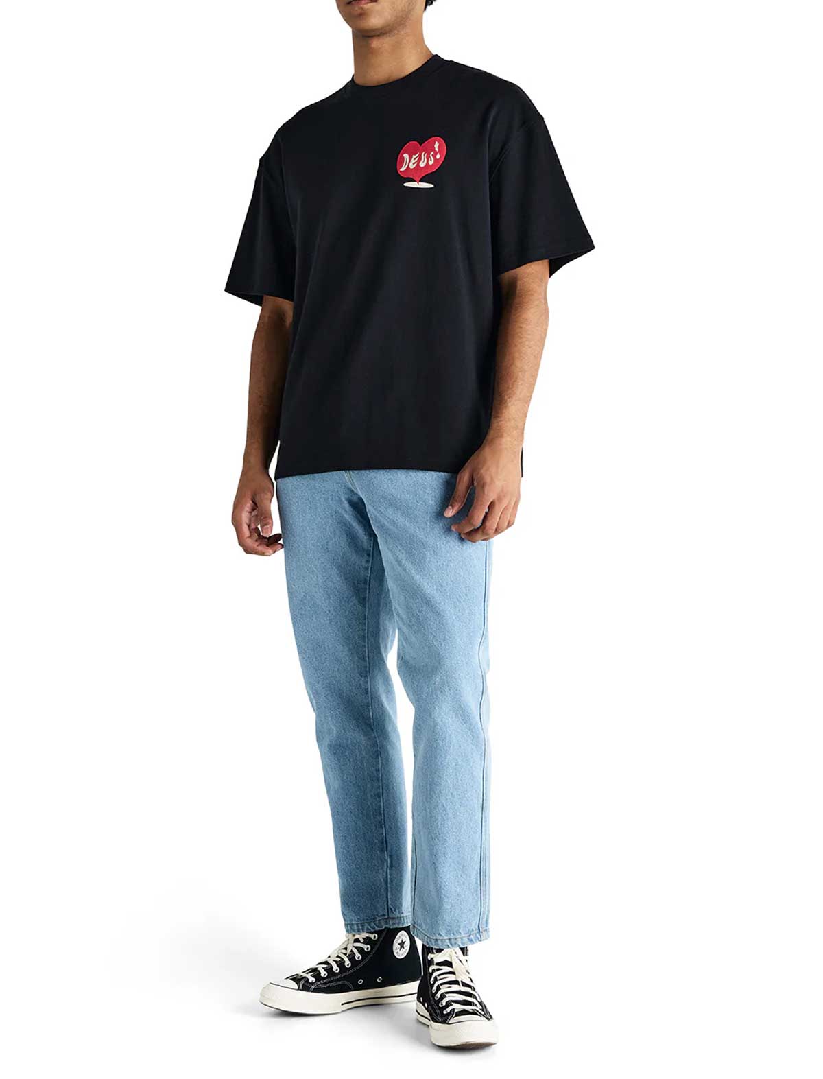 Person wearing a deus ex machina deep cut black t-shirt with a red graphic, light blue jeans, and black sneakers on a white background