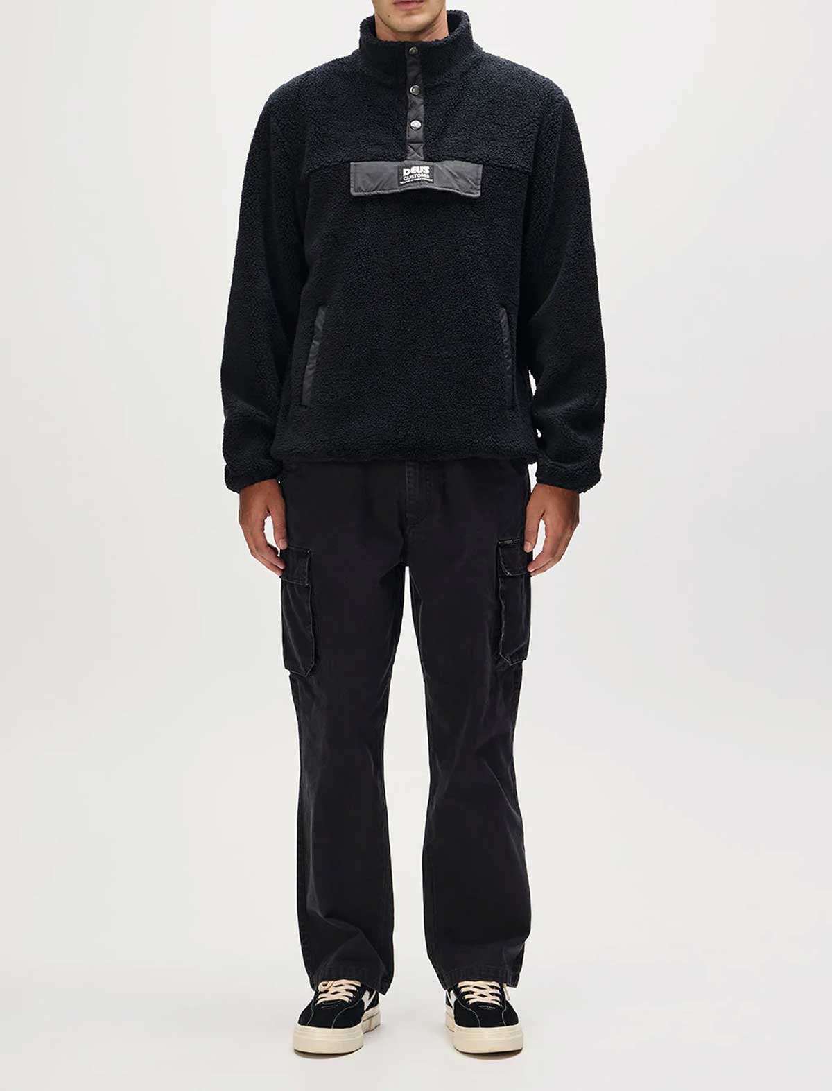 Person wearing a black fleece pullover and cargo pants on a white background