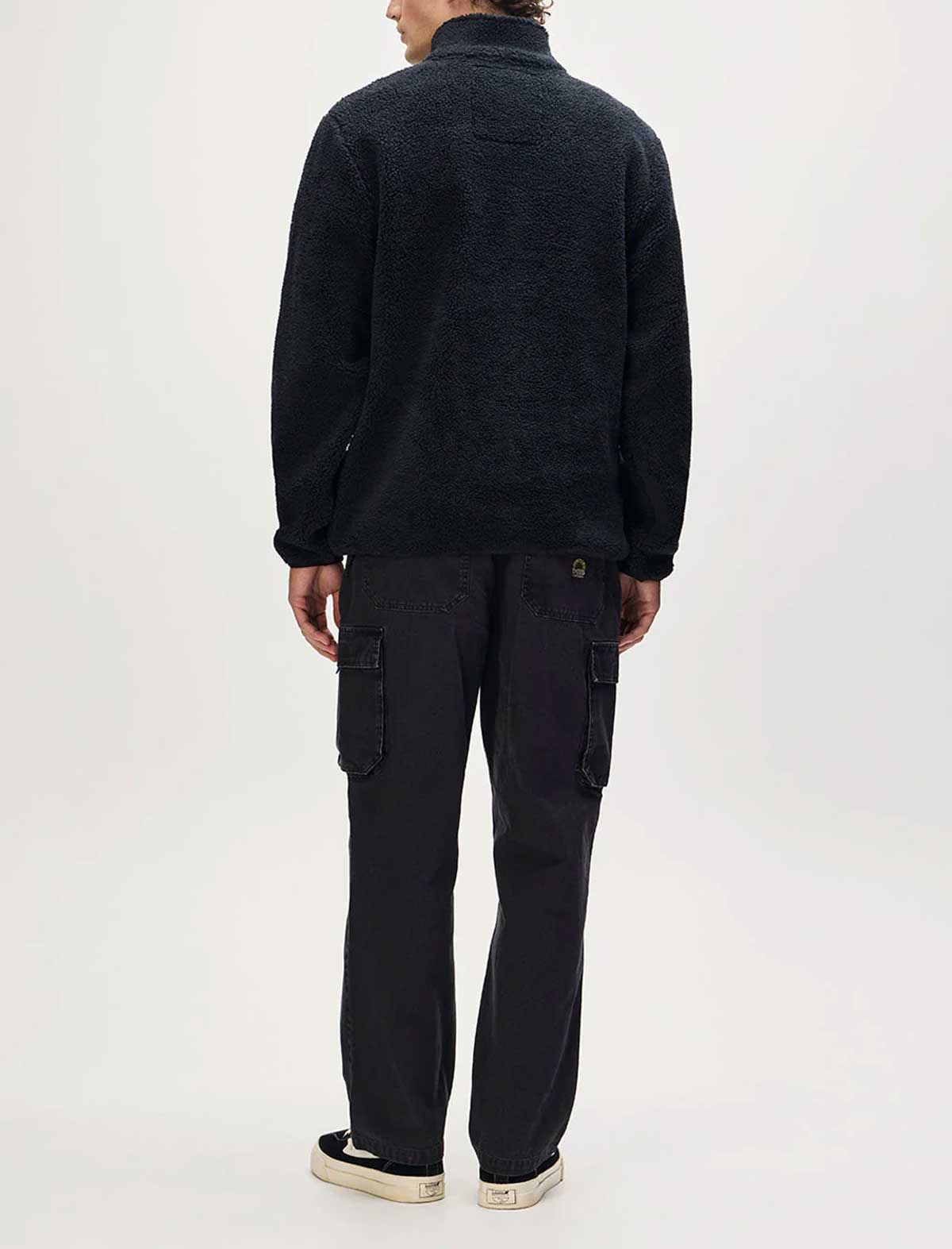 Person wearing a black jacket and cargo pants on a white background