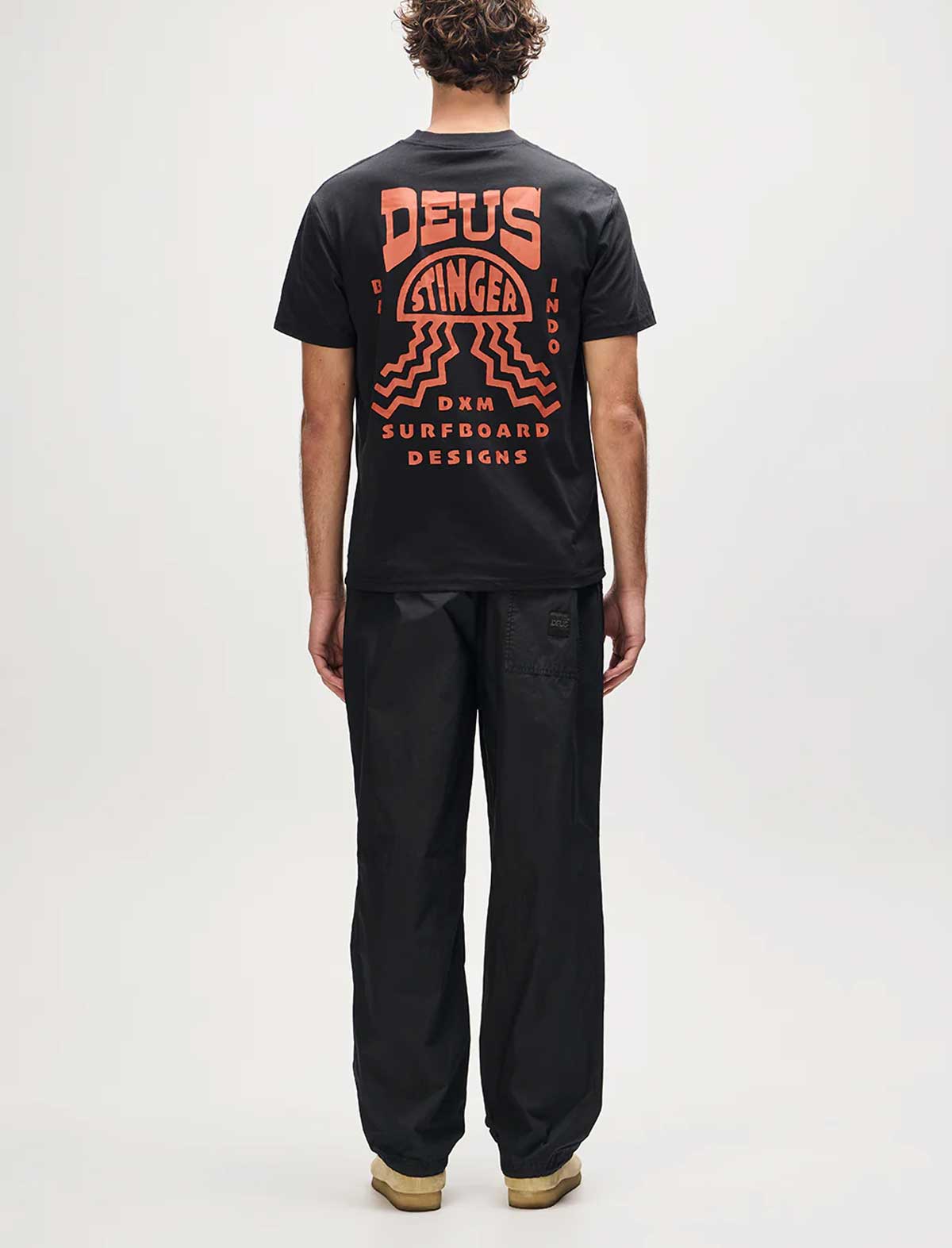 Person wearing a black t-shirt with red graphics and text on the back, standing against a white background.