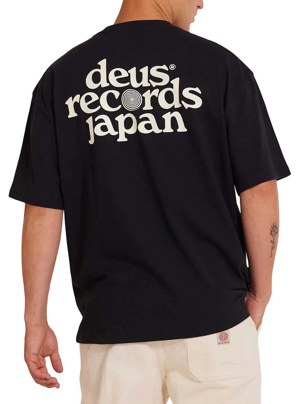 Person wearing a deus ex machina strata black t-shirt with 'deus records japan' text on the back.