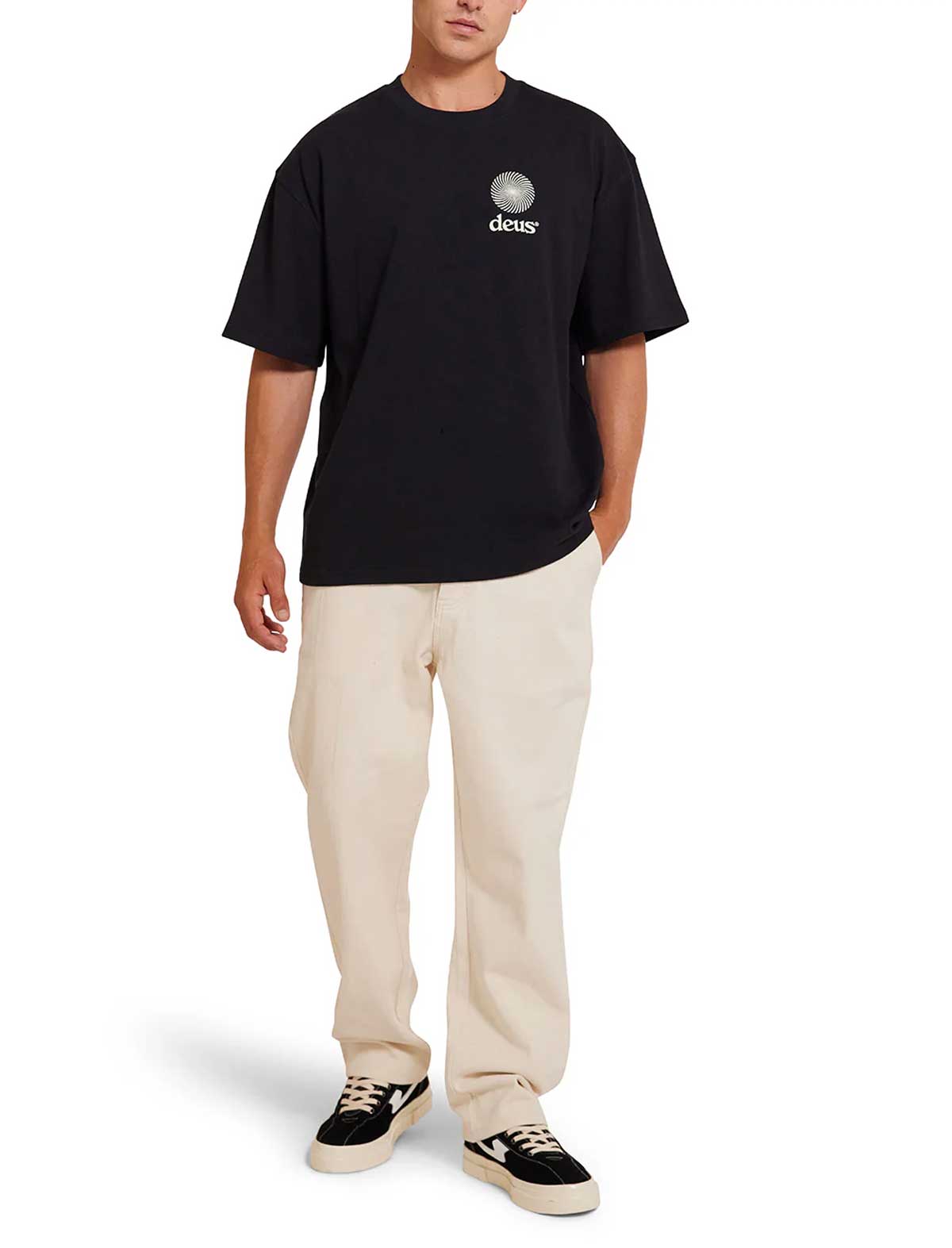Person wearing a deus ex machina strata black t-shirt with a logo and beige pants on a white background
