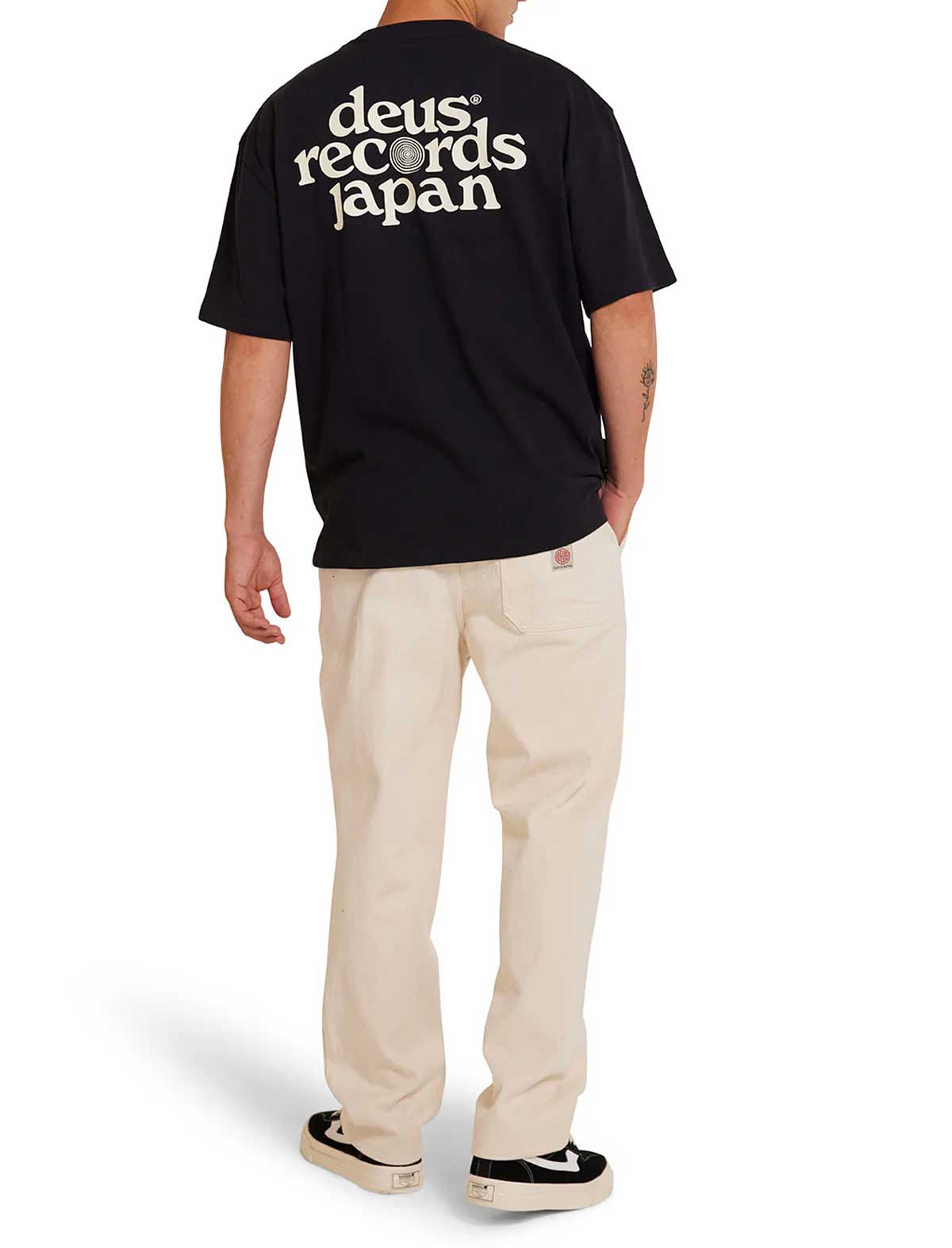 Person wearing a deus ex machina strata black t-shirt with 'deus records japan' text on the back, standing against a white background.