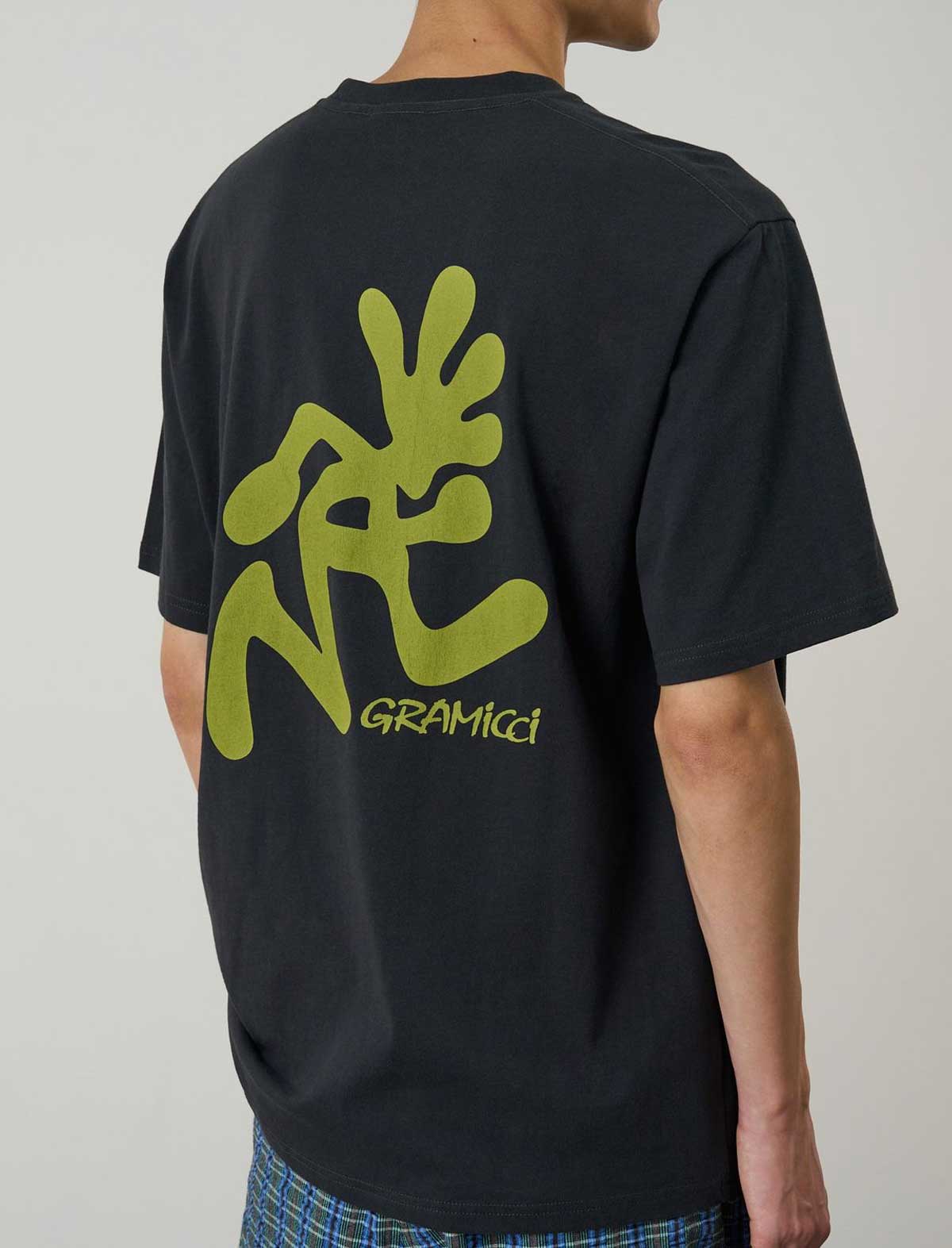 Person wearing a black t-shirt with green graphics and 'Gramicci' branding on the back.