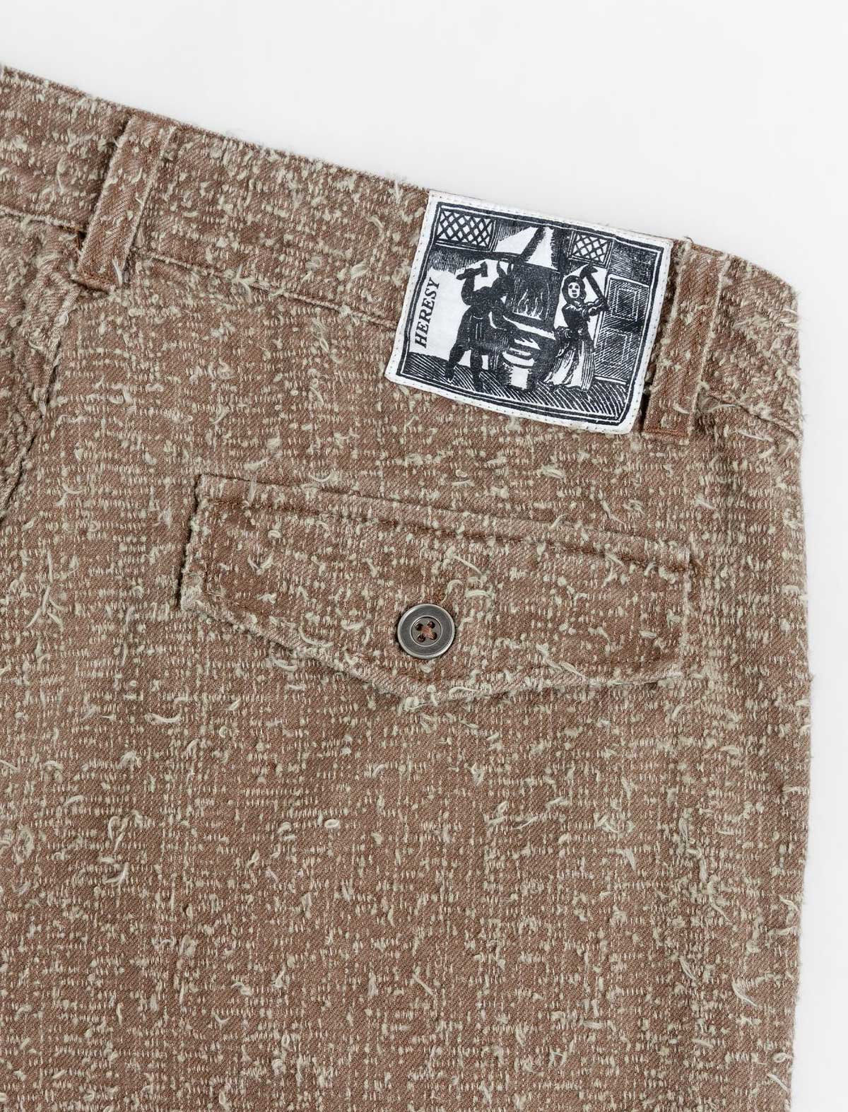 Close-up of brown textured fabric with a button and label on a white background