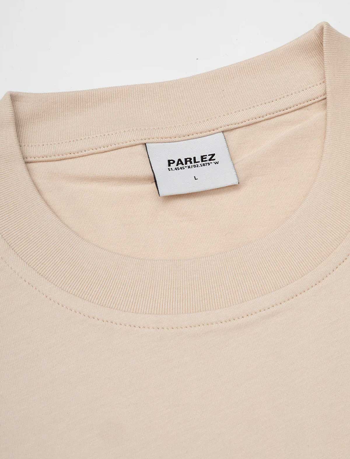 Close-up of a beige t-shirt with a Parlez label on a white background