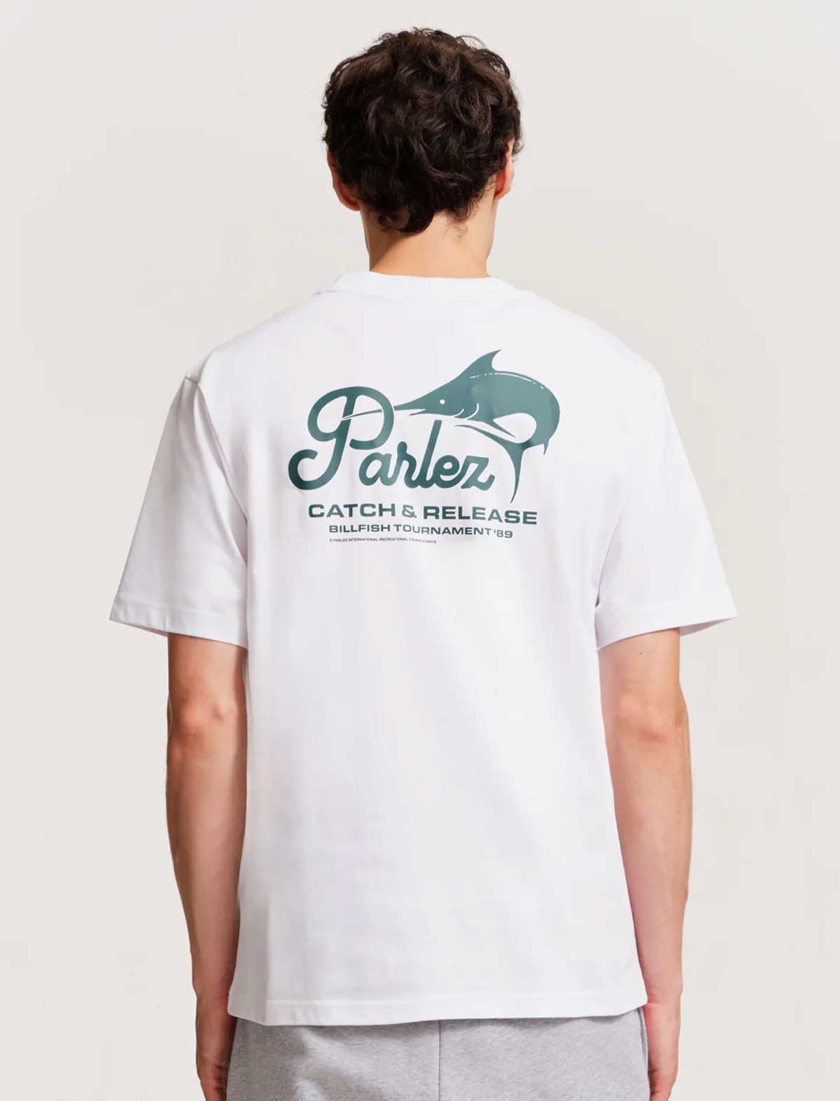 Person wearing a white t-shirt with a Parlez logo on the back against a plain background