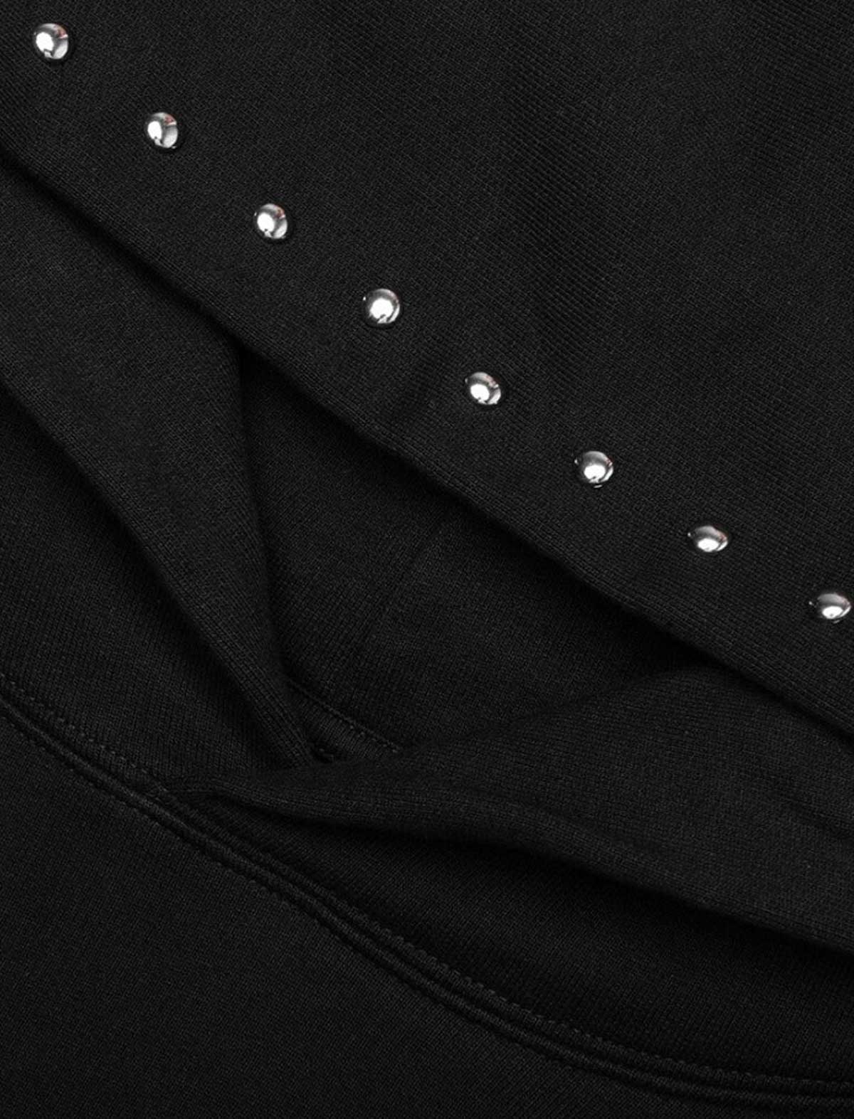 Close-up of a black garment with silver studs on a dark background