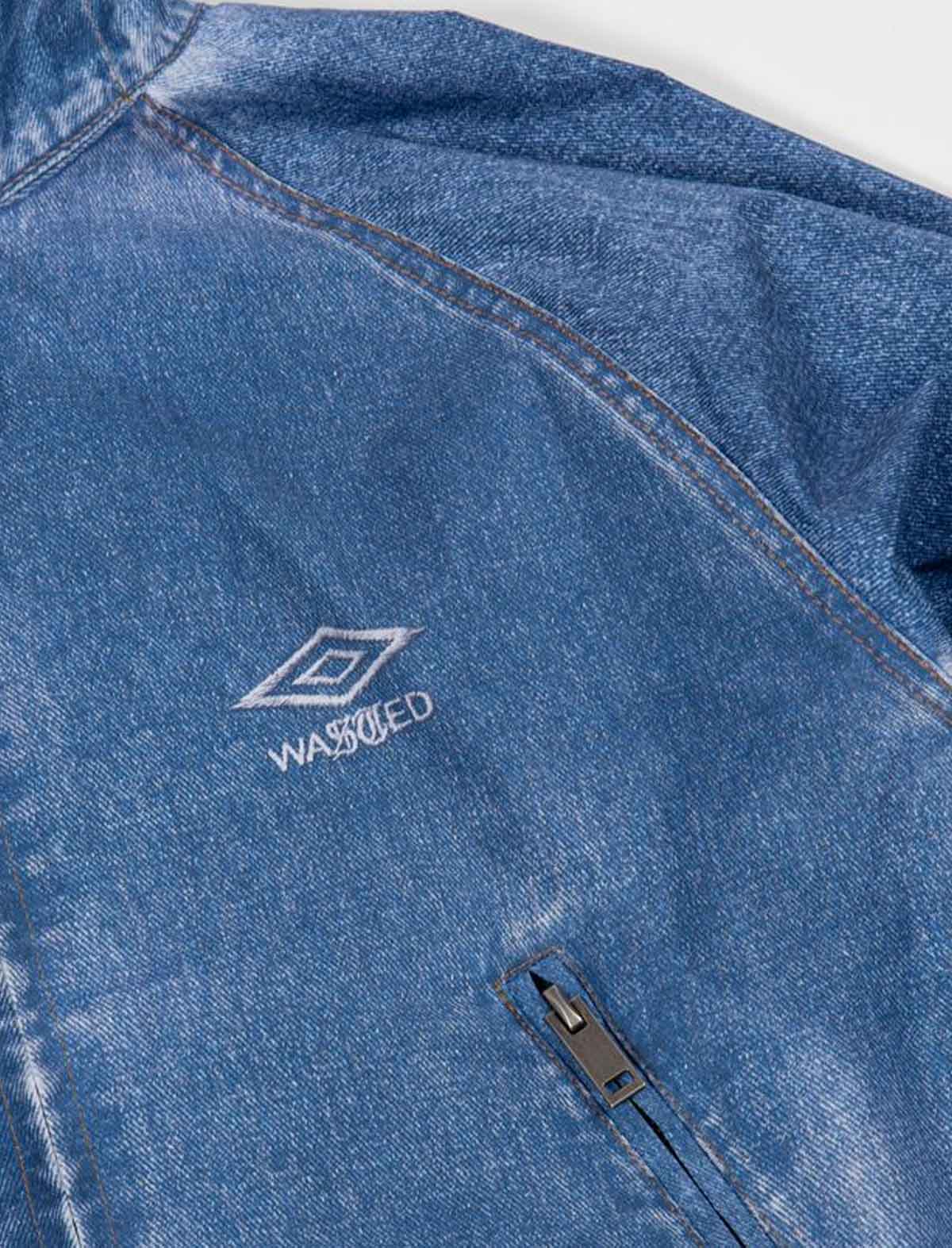 Close-up of a Wasted Paris x Umbro Trompe L'Oel Windbreaker blue denim jacket with a brand logo on a white background