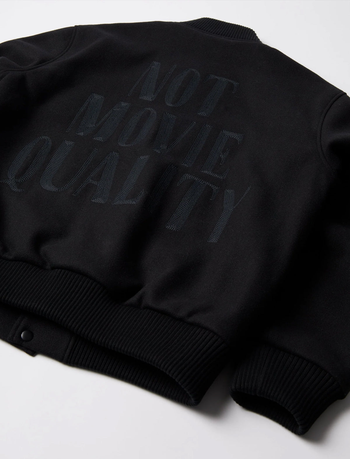 Black bomber jacket with 'Not Movie Quality' text on a white background