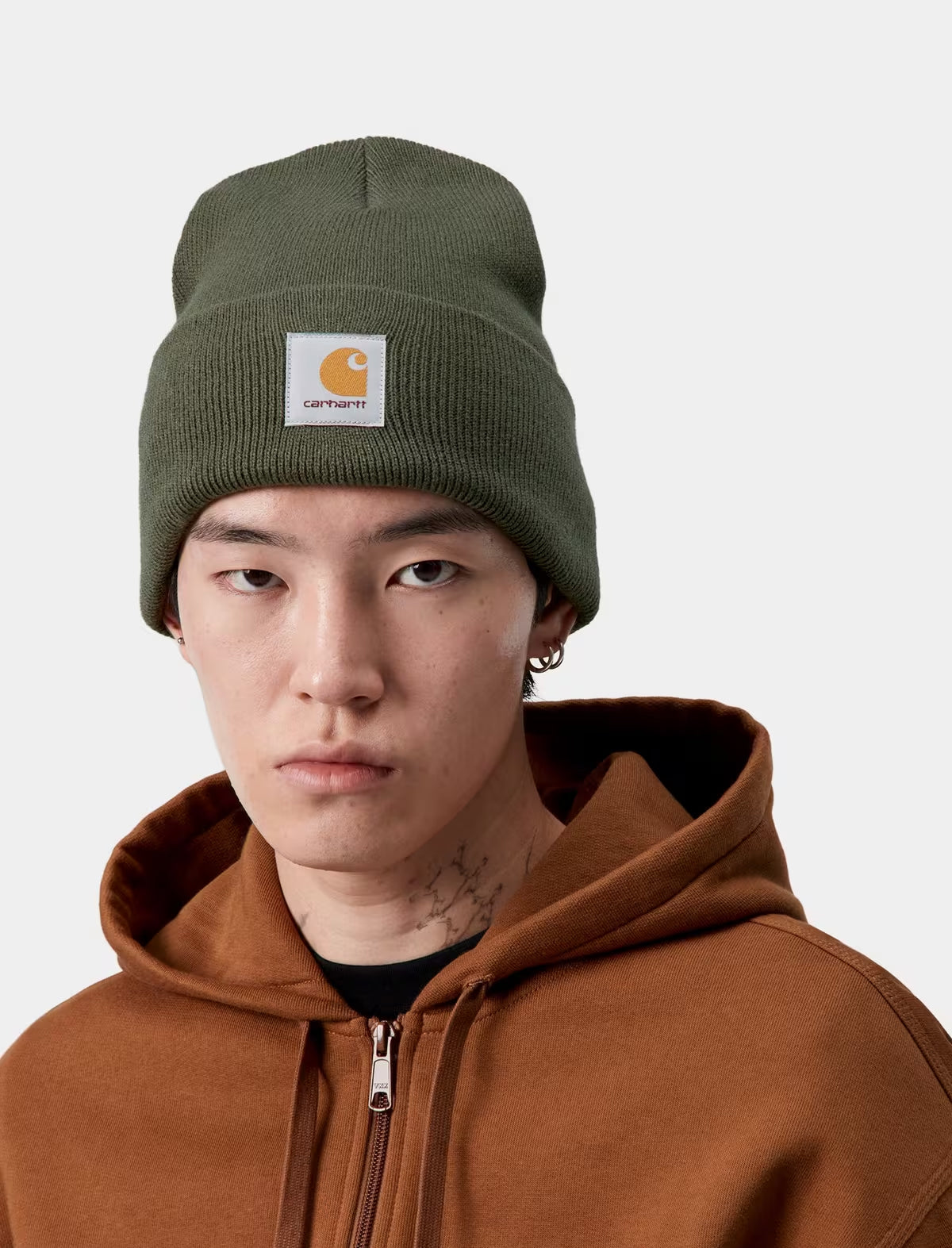 Person wearing a green beanie with a Carhartt logo on a white background