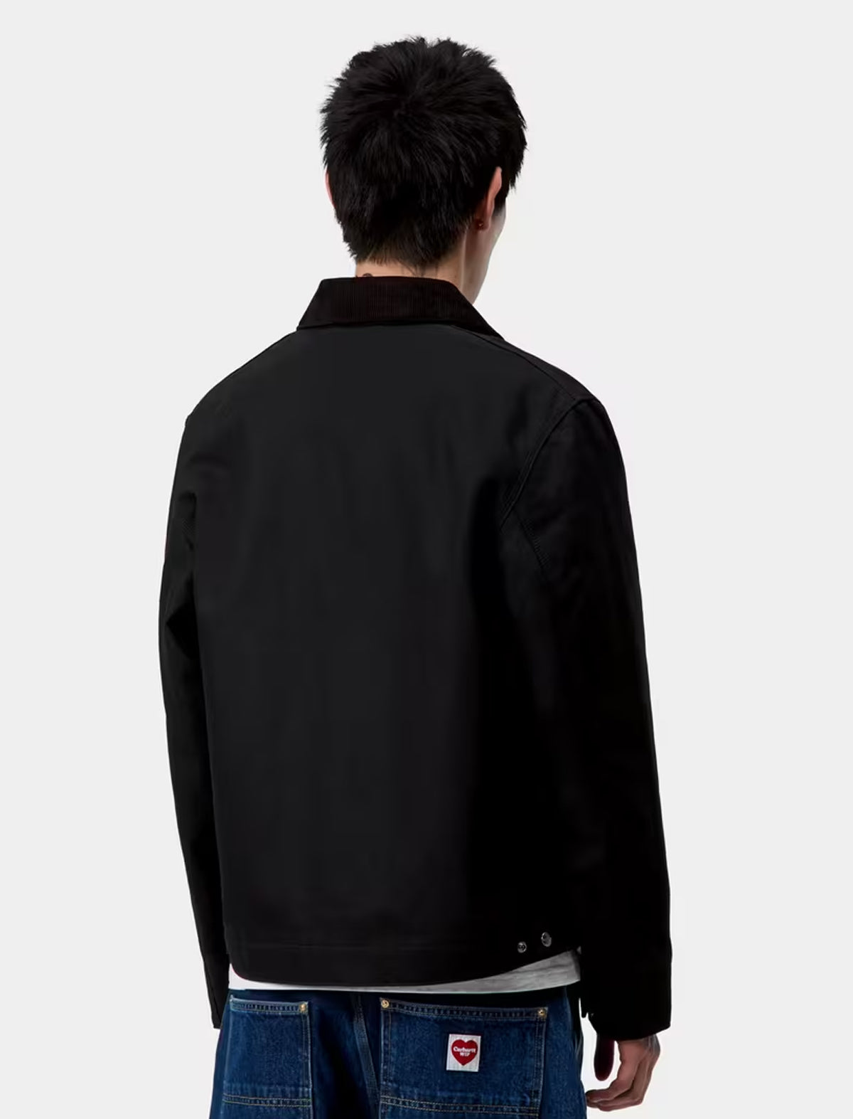 Person wearing a carhartt detroit black jacket on a white background