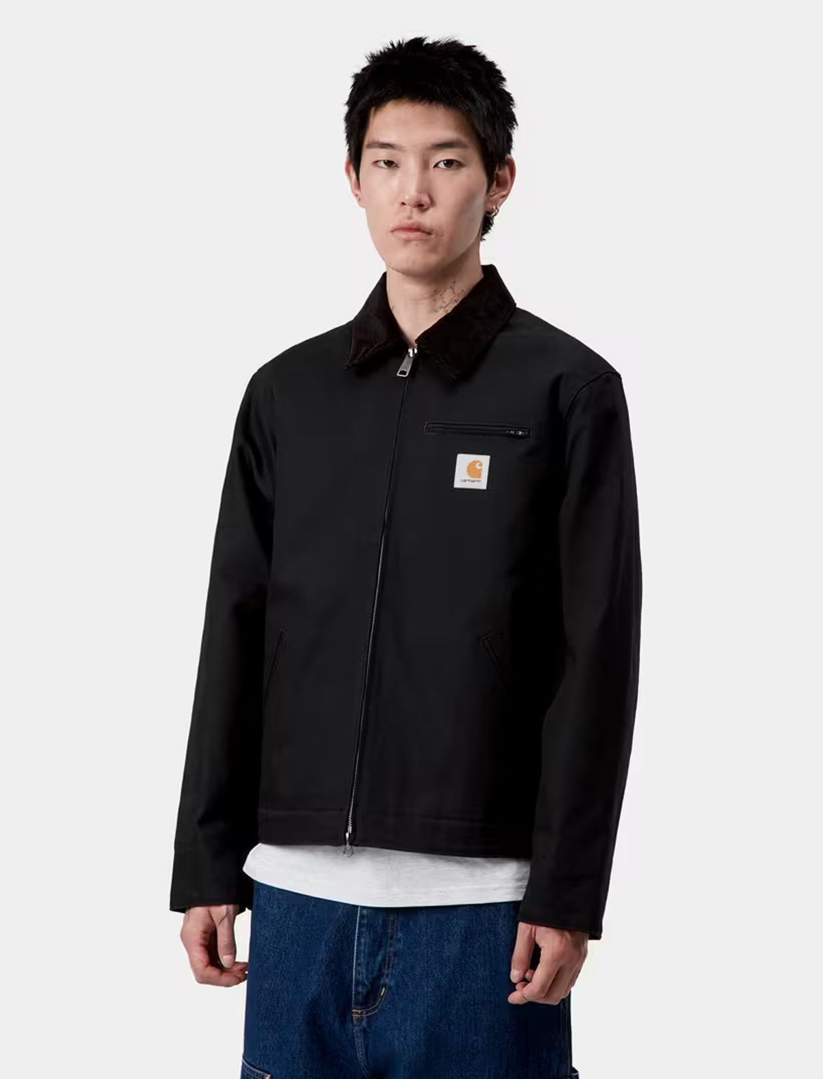 Person wearing a carhartt detroit black jacket with a visible brand logo on a white background