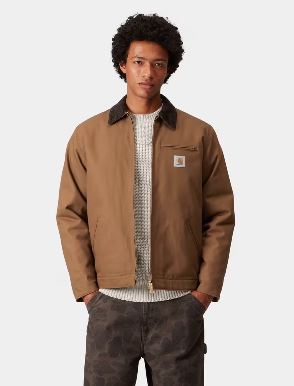 Man wearing a carhartt detroit brown jacket with a visible brand logo on a white background