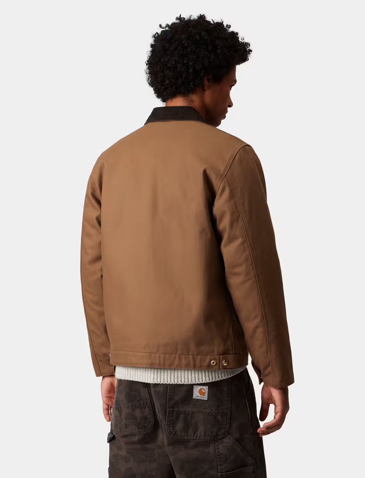 Person wearing a carhartt detroit brown jacket on a plain background