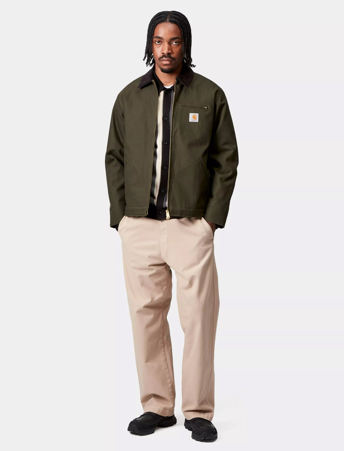 Man wearing a Carhartt WIP Detroit green jacket with a brand logo on a white background