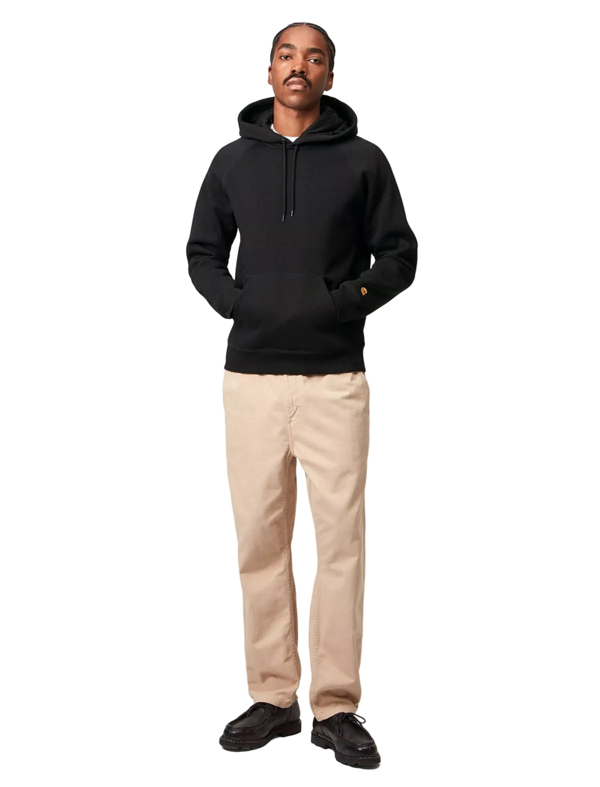 Person wearing a black hoodie and beige pants on a white background