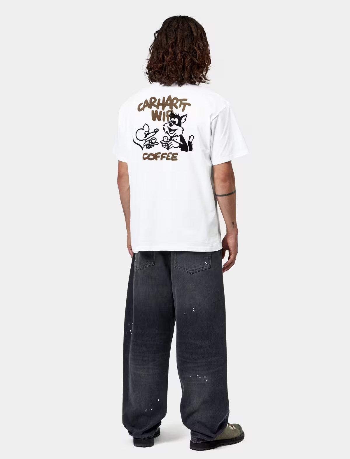 Person wearing a white t-shirt with a graphic design on the back, standing against a white background.