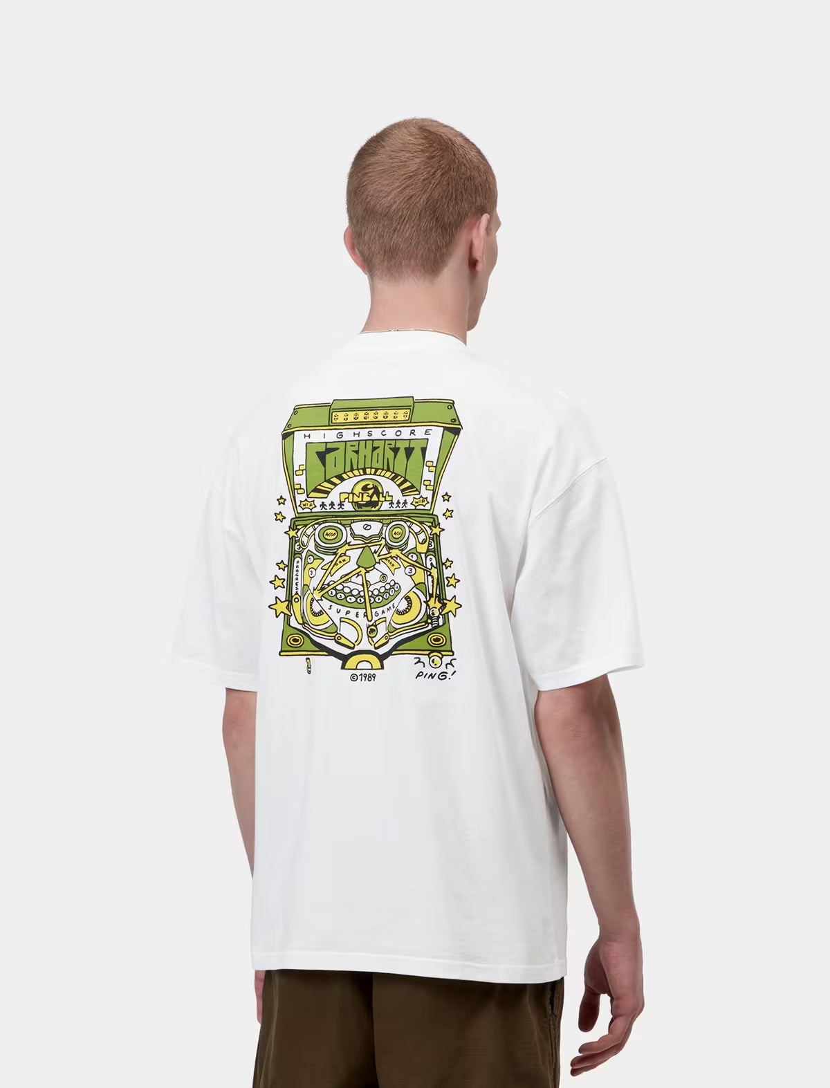 Person wearing a white t-shirt with a colorful graphic design on the back, standing against a white background.