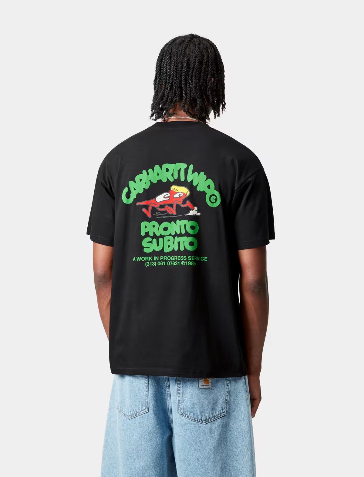 Person wearing a carhartt wip pronto black t-shirt with green and red graphics on the back, standing against a white background