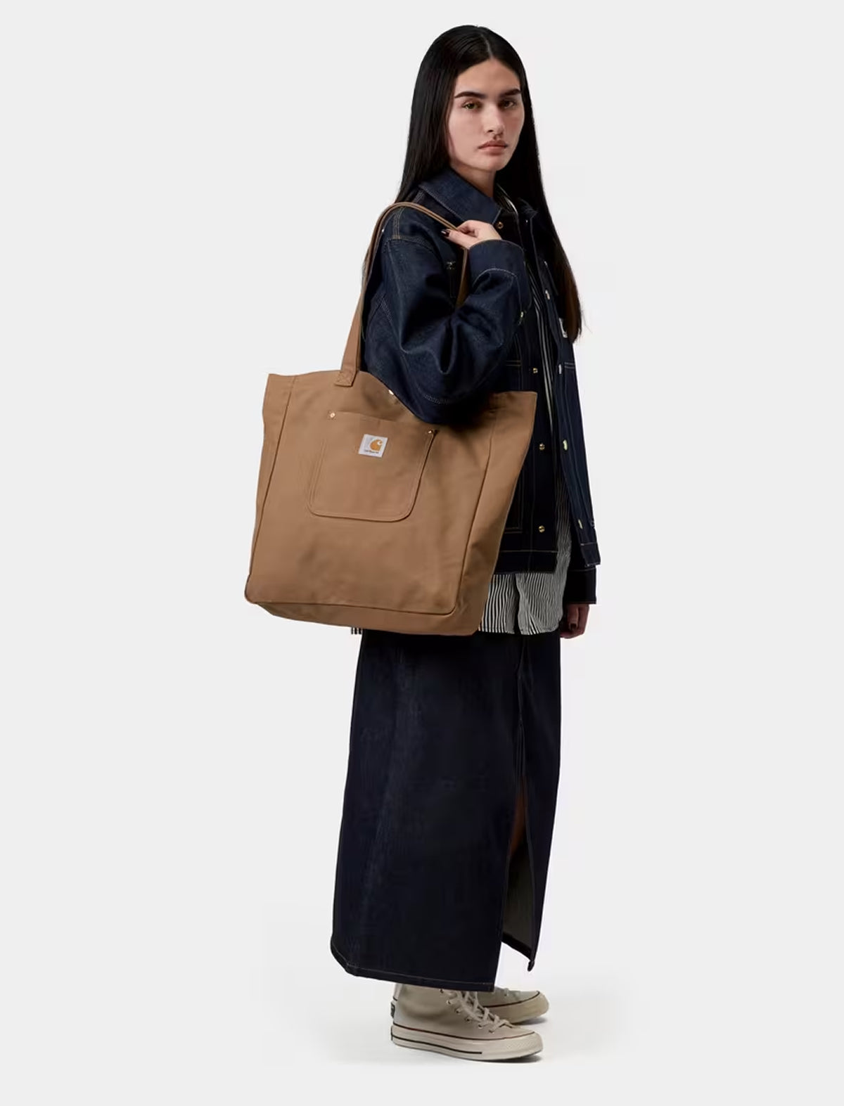 Person holding a carhartt wip brown tote bag against a white background