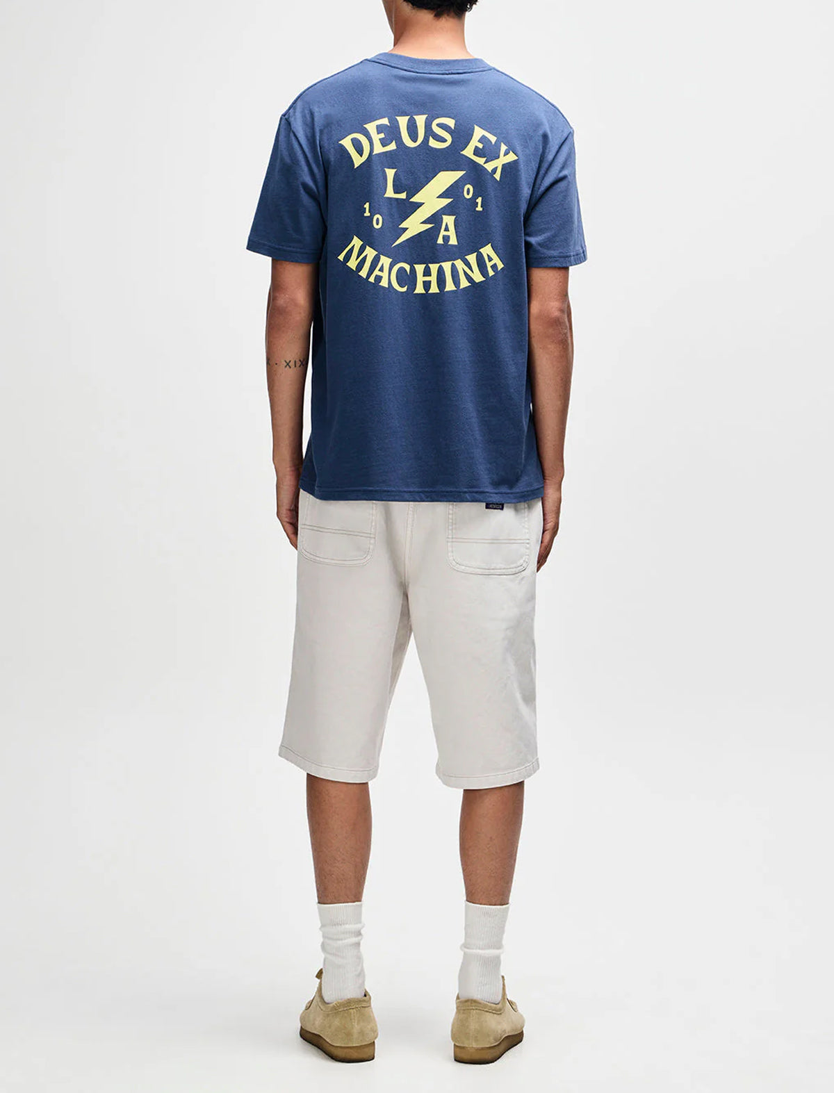 Person wearing a blue 'Deus Ex Machina' t-shirt with a white background
