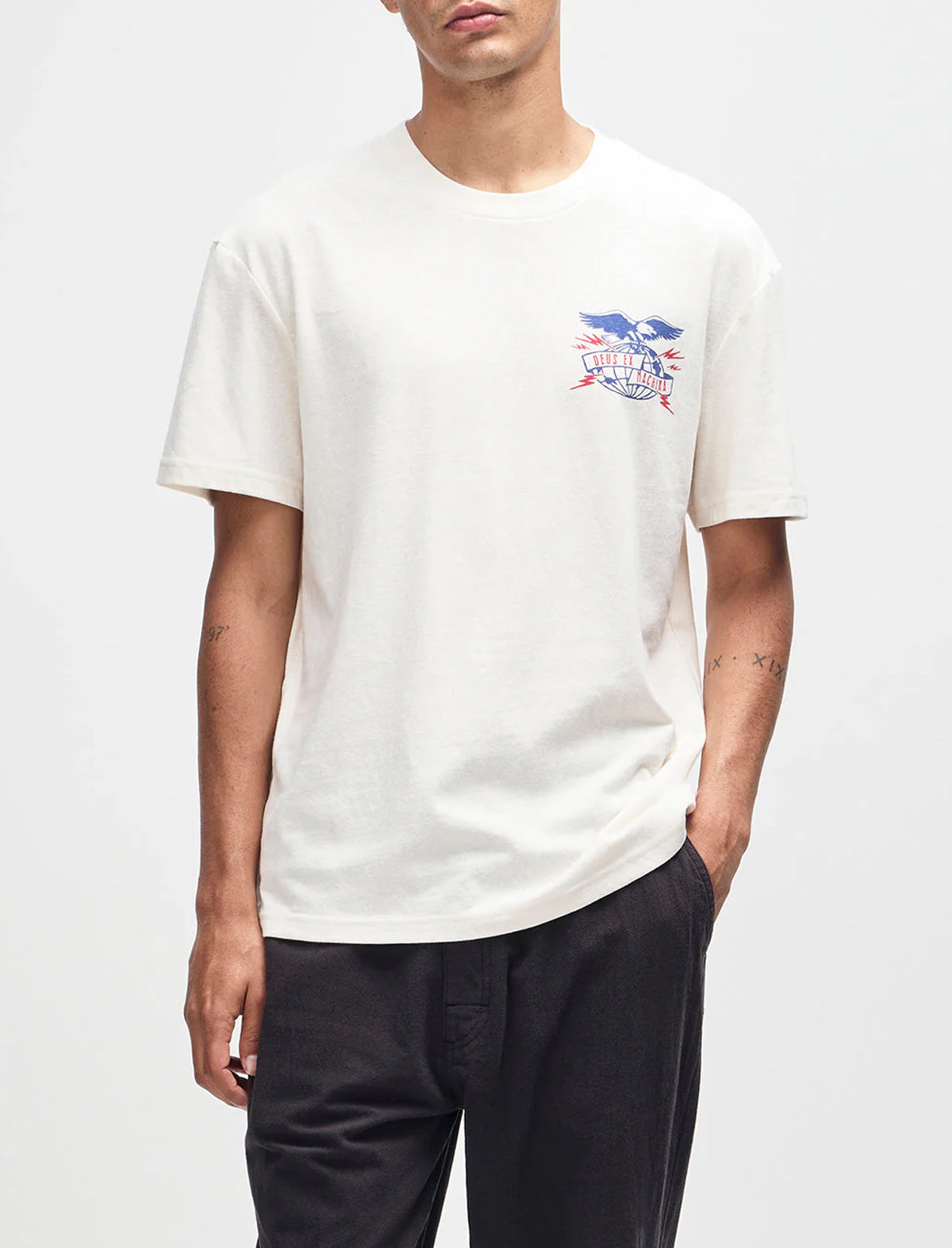 Person wearing a white t-shirt with a graphic design on a plain background