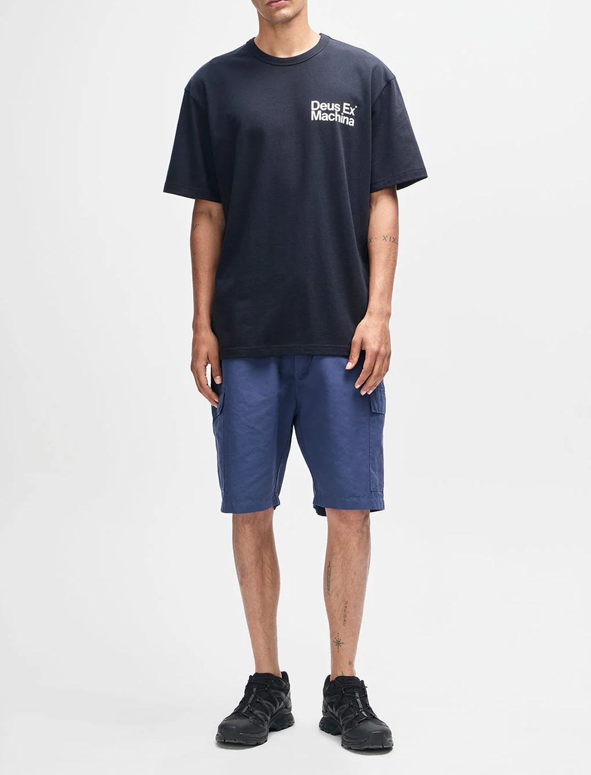 Person wearing a navy t-shirt with text and blue shorts on a white background