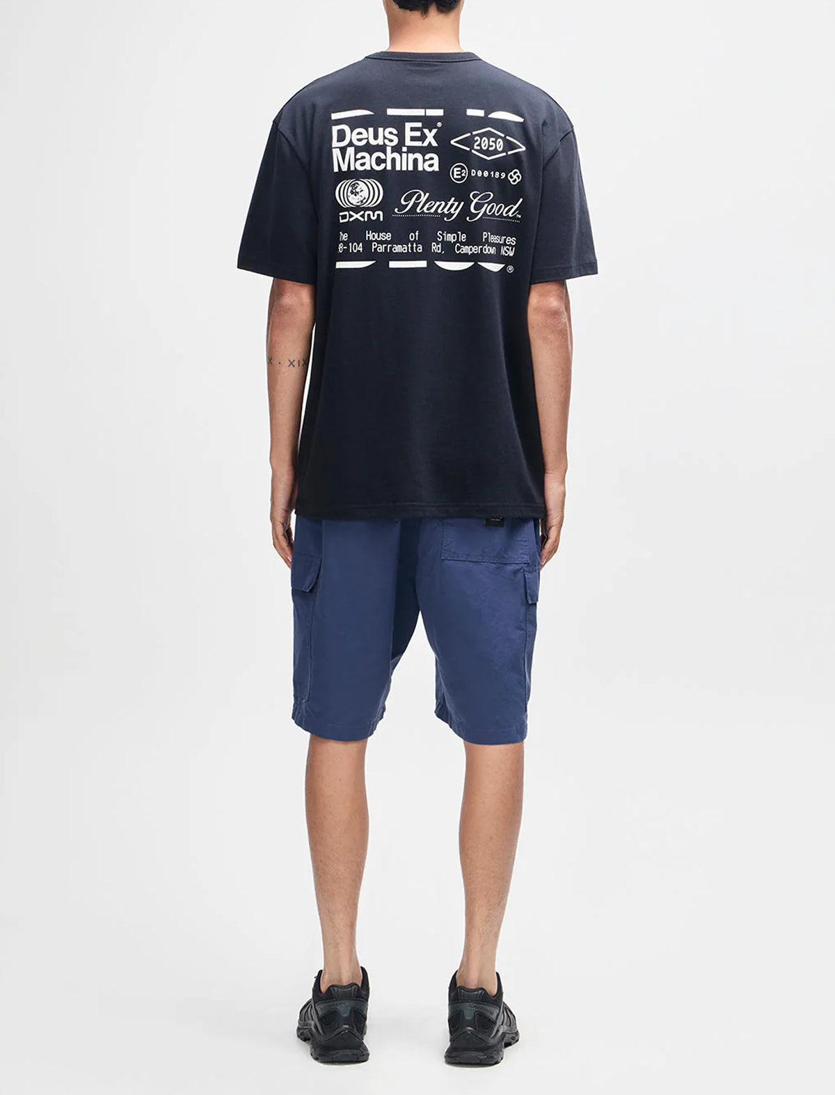 Person wearing a navy t-shirt with branding and text, standing against a white background