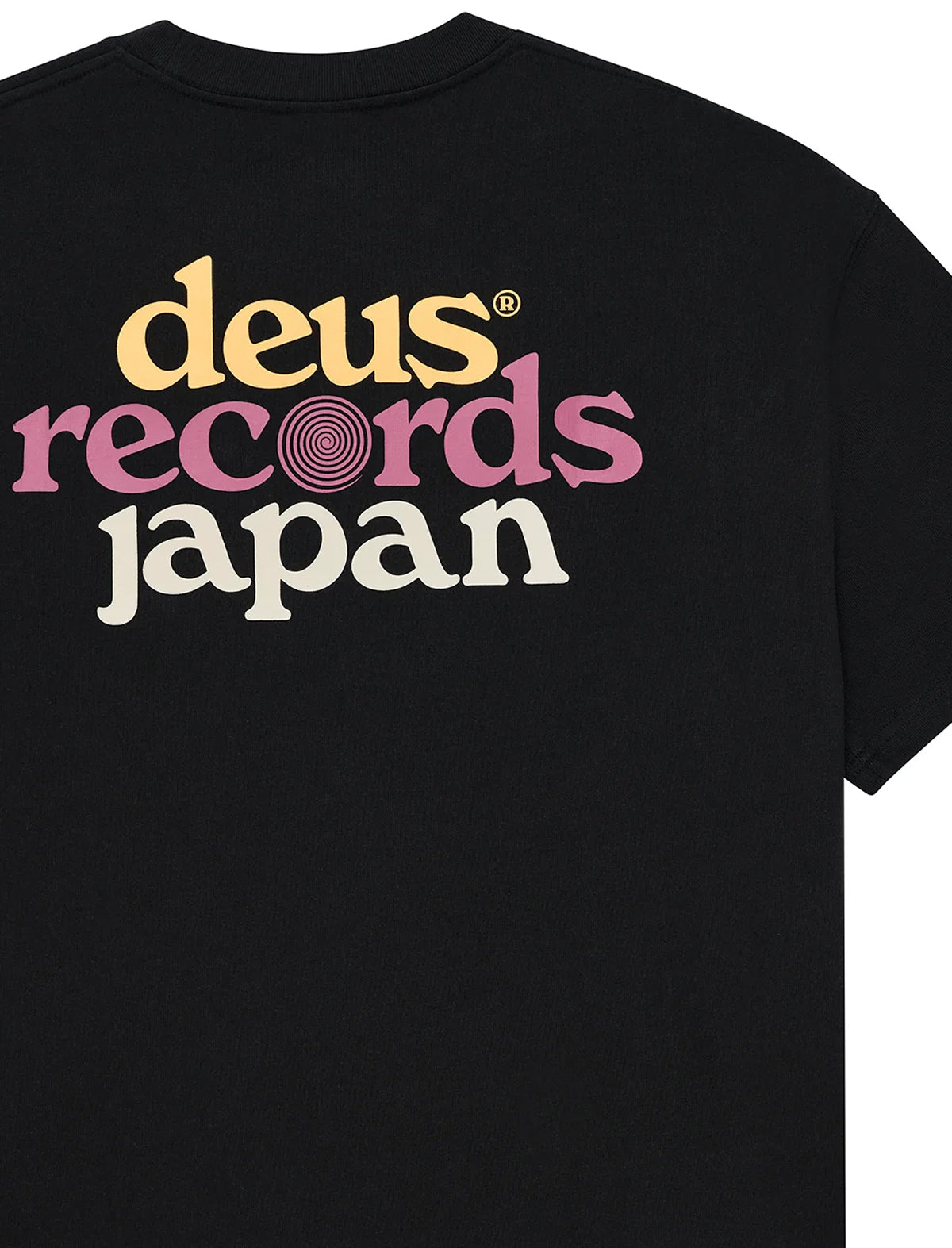 Close-up of the back of a black short-sleeve T-shirt with a large retro-style text graphic reading 'deus records japan' in yellow, pink, and off-white lettering.