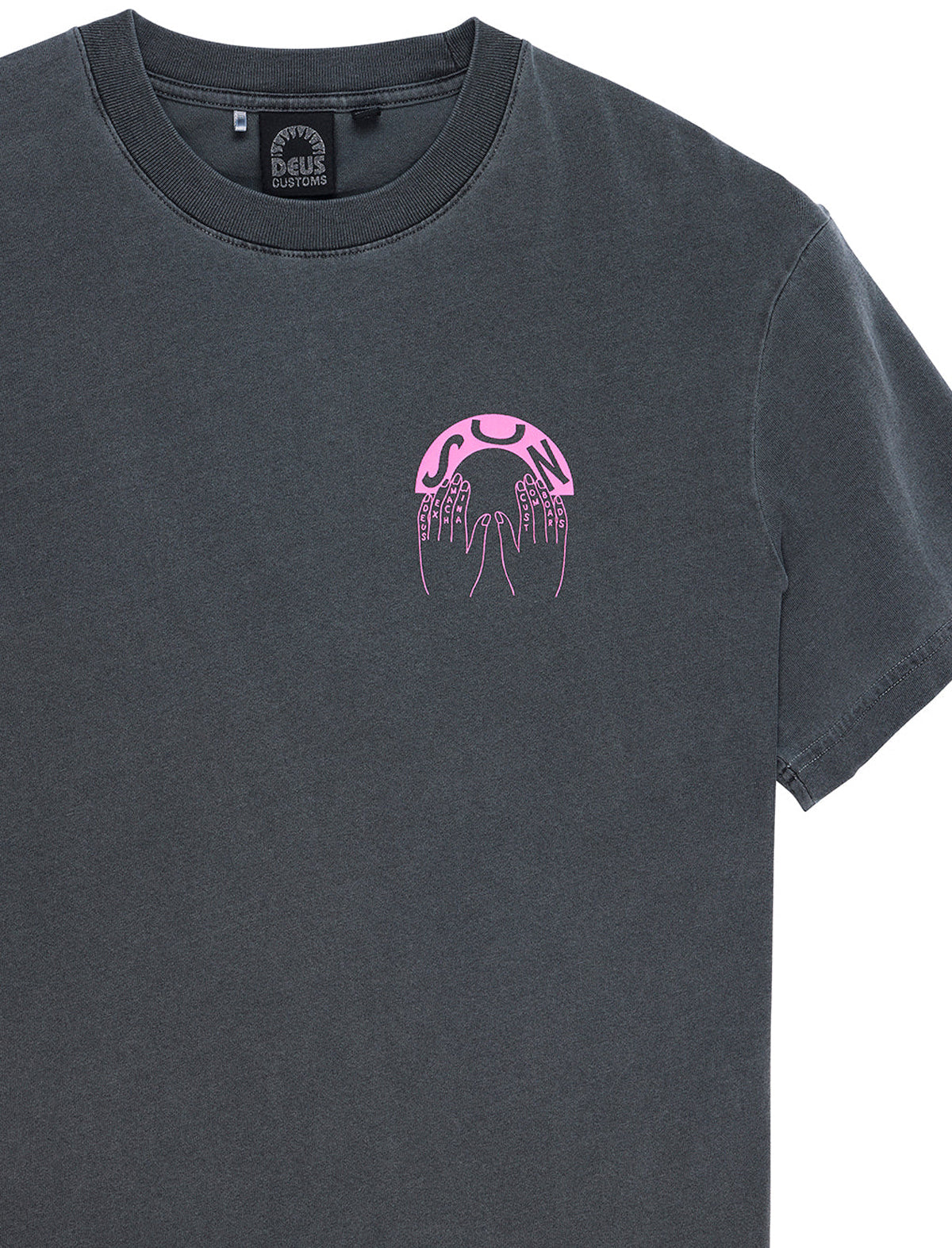 A dark charcoal gray crewneck t-shirt featuring a small pink graphic on the left chest depicting a stylized skull with sharp teeth and the words 'BONE SHATTER'. The inner neck label shows the brand 'DEUS CUSTOMS'.