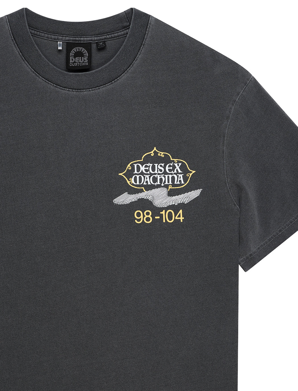 A close-up of a dark charcoal gray t-shirt featuring a graphic on the left chest with the text 'DEUS EX MACHINA' in white, a white wing, and '98-104' in gold.