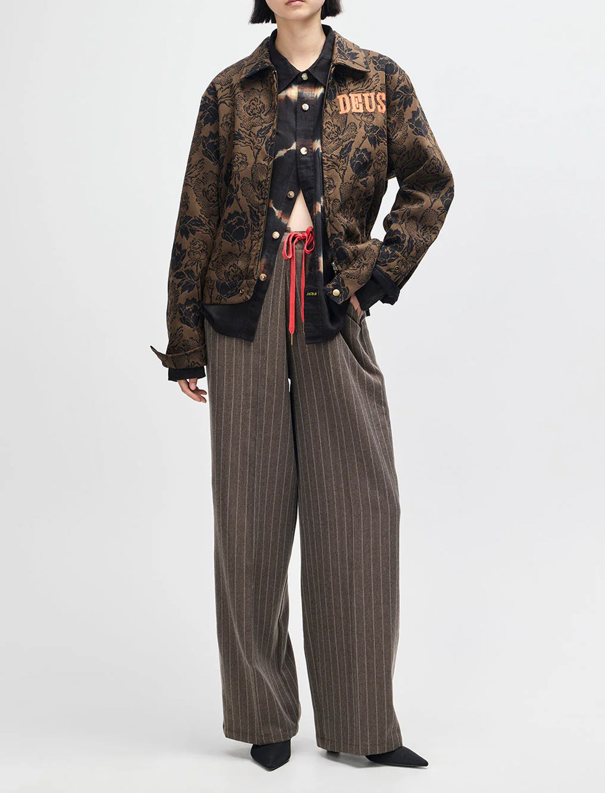 Person wearing a patterned jacket and pinstripe pants on a white background