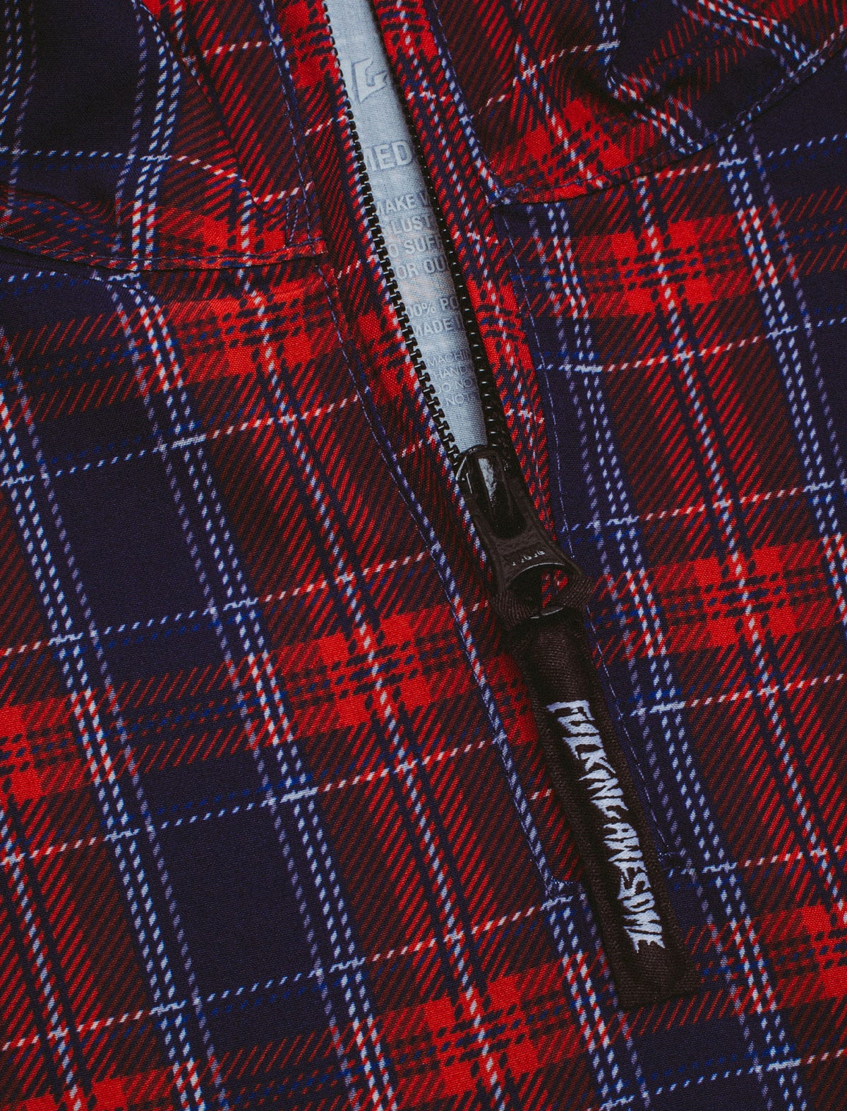 Close-up of a plaid jacket with a zipper, featuring the branded zipper pull