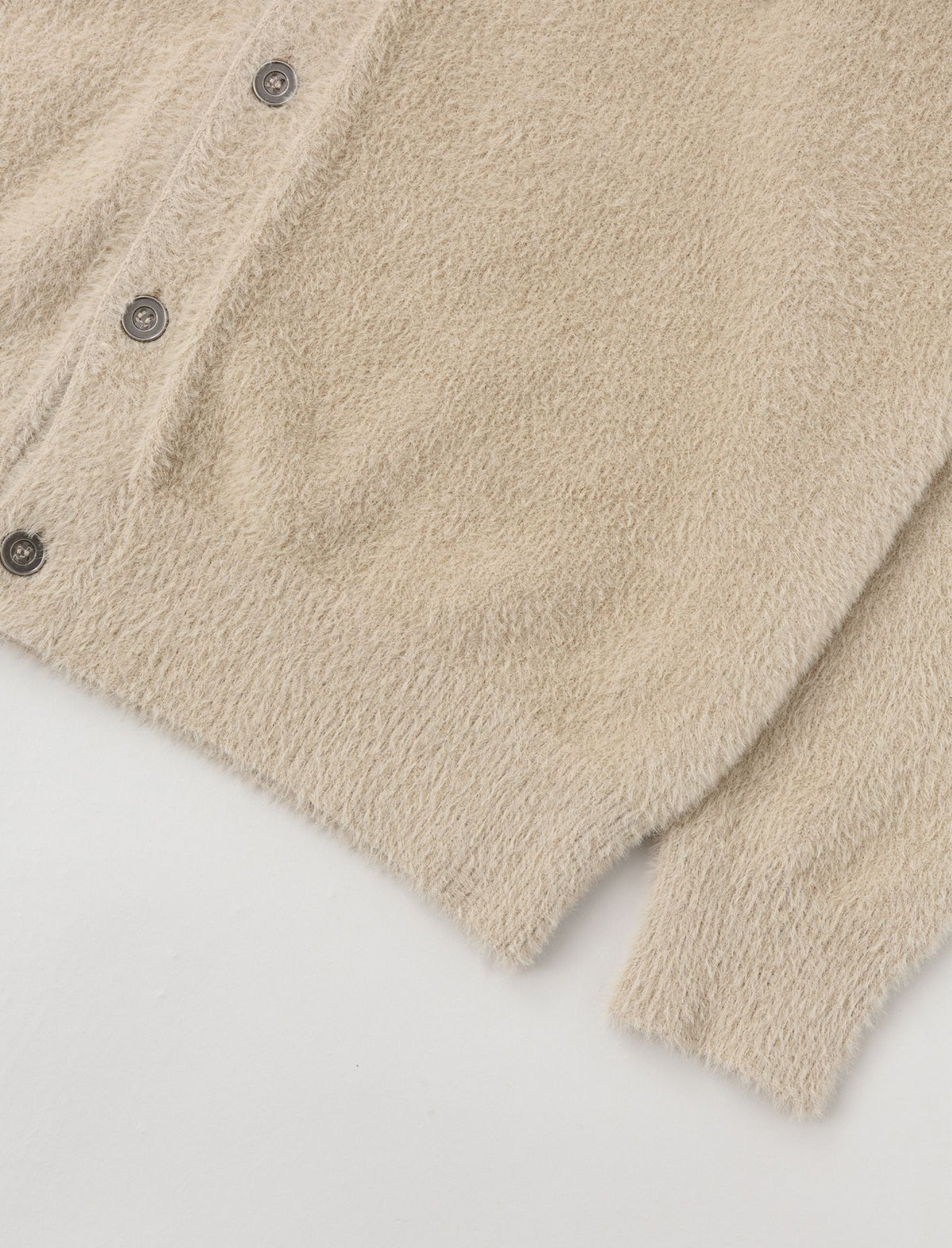 Heresy 'H' Cardigna close-up of a beige fleece jacket with buttons on a light gray background