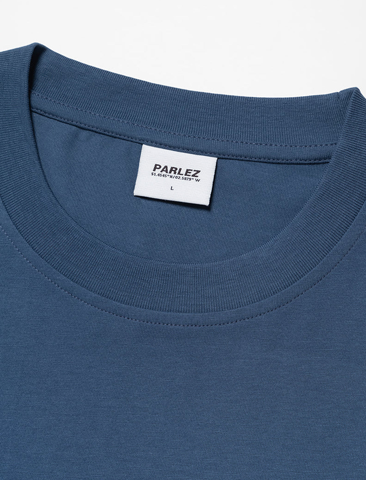 Close-up of a blue t-shirt with a Parlez label on a white background