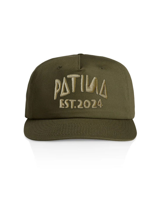 An olive green snapback cap with 'PATINA EST. 2024' embroidered on the front in a contrasting tan color, shown against a plain white background.