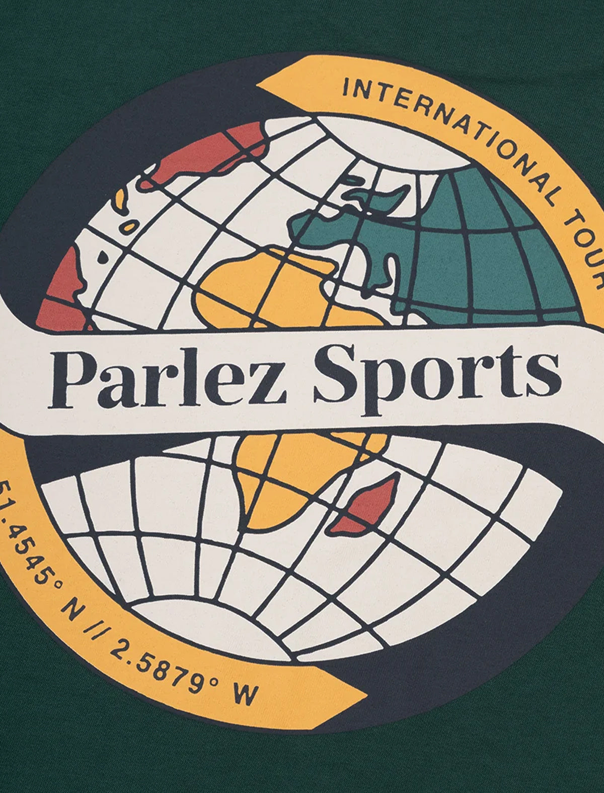 A close-up of a dark green garment featuring a circular graphic print. The design includes a stylized globe with continents in yellow, teal, and red, a curved yellow banner reading 'INTERNATIONAL TOUR', and a central white banner with the text 'Parlez Sports'.