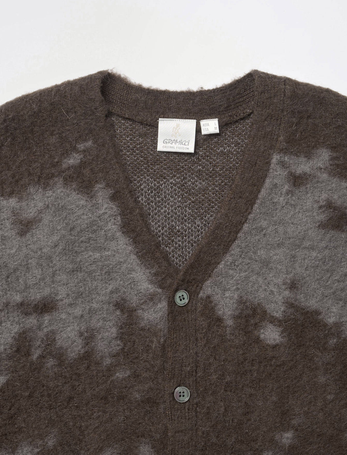 A close-up of a brown and gray tie-dye knit cardigan sweater with a V-neck and button closure, showing a brand label that reads 'GODAY!'.