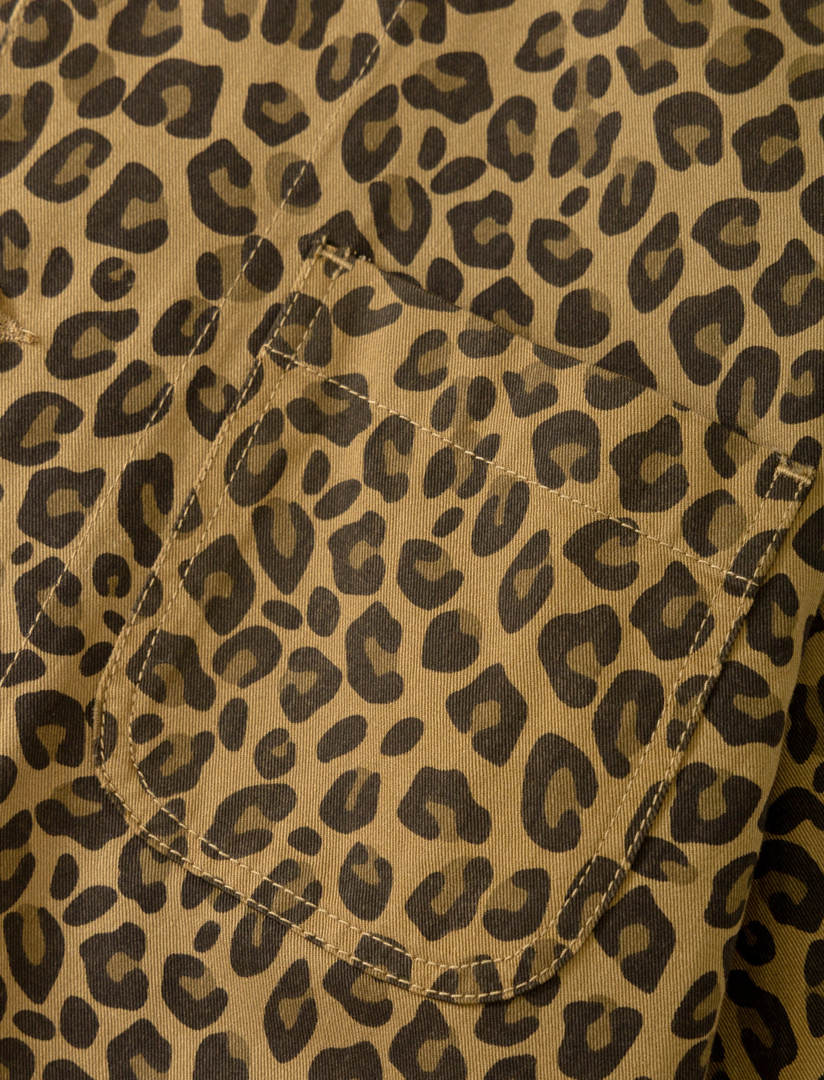 Close-up of a leopard print fabric with a pocket, featuring a tan background with dark brown and black spots.