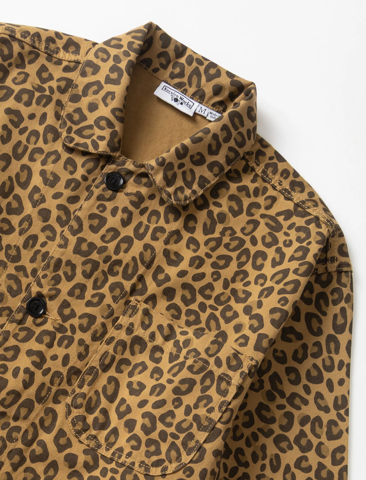 A close-up of a brown and tan leopard print button-down shirt with a pointed collar and a visible 'Service Works' neck label.